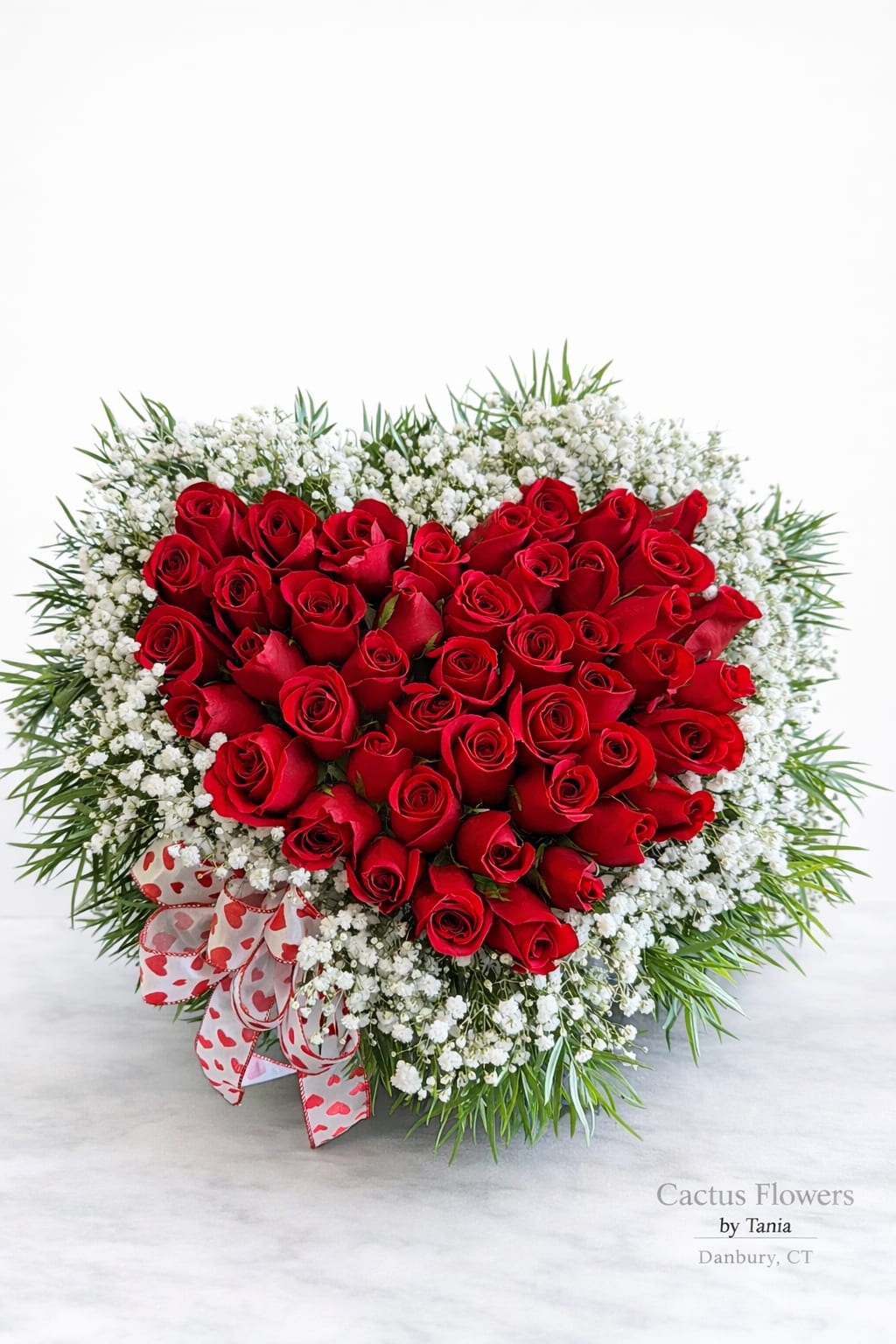 Love Heart – by Cactus Flowers - A bold and romantic heart-shaped arrangement designed exclusively by Cactus Flowers by Tania.  Premium red roses are carefully arranged in a perfect heart, surrounded by delicate baby’s breath and lush greenery for a timeless, elegant finish.  This design speaks without words — it’s love, passion, and intention in every bloom.