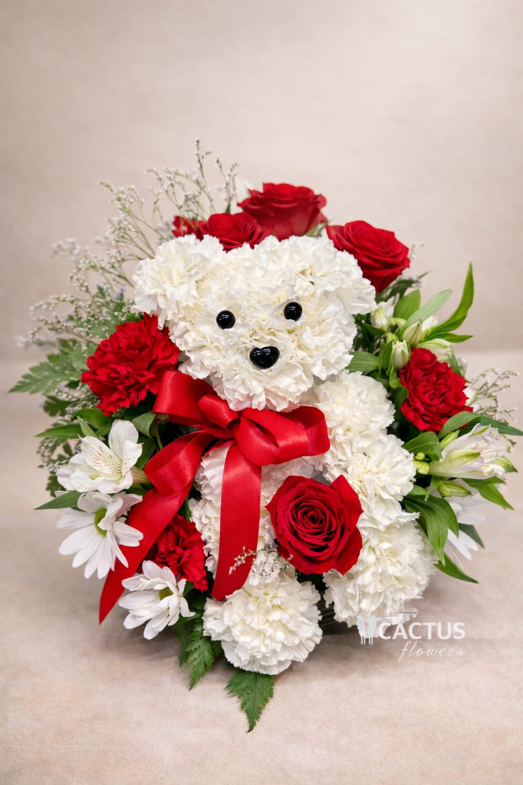 Max – The Signature Floral Pup - Meet Max – The Signature Floral Pup, a handcrafted floral arrangement designed to melt hearts.  This adorable puppy is carefully shaped with fresh white carnations and accented with premium red roses, seasonal blooms, lush greenery, and a signature red satin ribbon. Designed in a charming basket, Max is both playful and elegant — making it the perfect gift for birthdays, anniversaries, romantic surprises, get well wishes, or just because.  Each arrangement is handcrafted by Cactus Flowers by Tania using fresh, high-quality blooms. Flower varieties may vary slightly based on availability while maintaining the overall look, color palette, and design style.