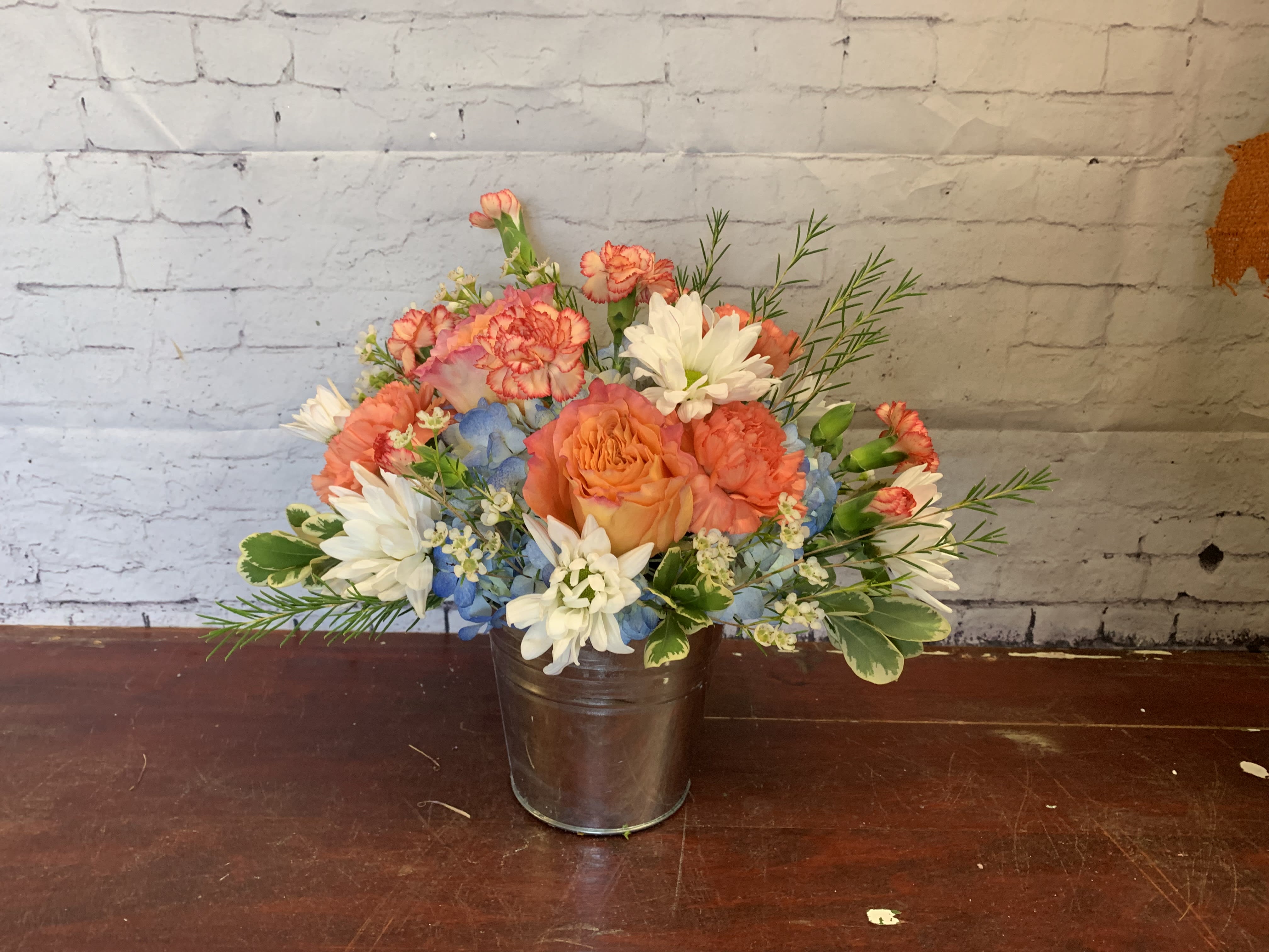 Something in the orange - Tin bucket with blue hydrangea and white daisies in a mix of orange florals 