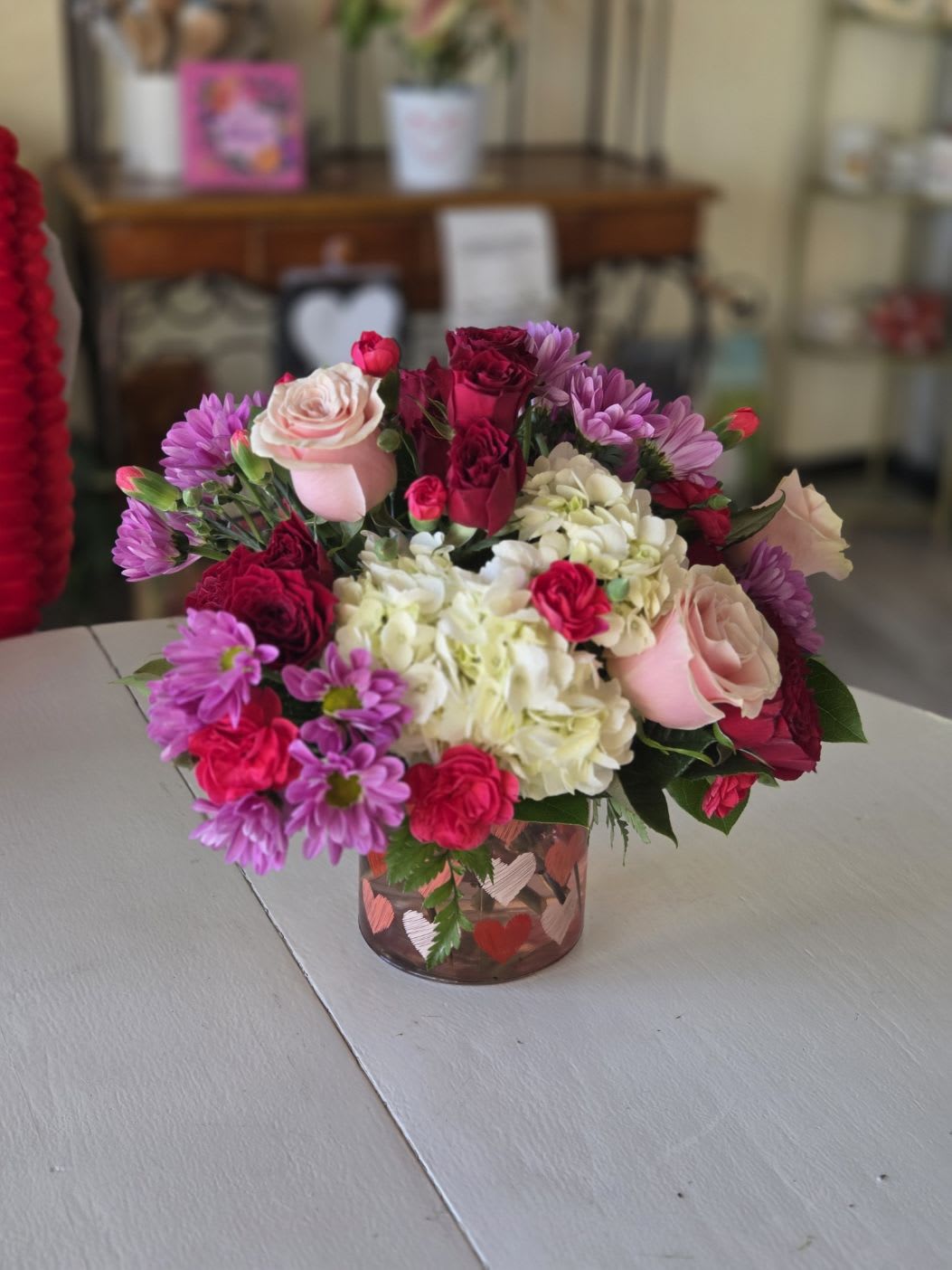 Cupid’s Garden - A modern Valentine’s arrangement featuring soft blush roses, rich berry-toned blooms, crisp white hydrangea, and fresh lavender accents. Designed in a sleek glass vase with subtle heart detailing, Blush + Berry balances romance with contemporary style—perfect for saying “I love you” in an effortless, elevated way.