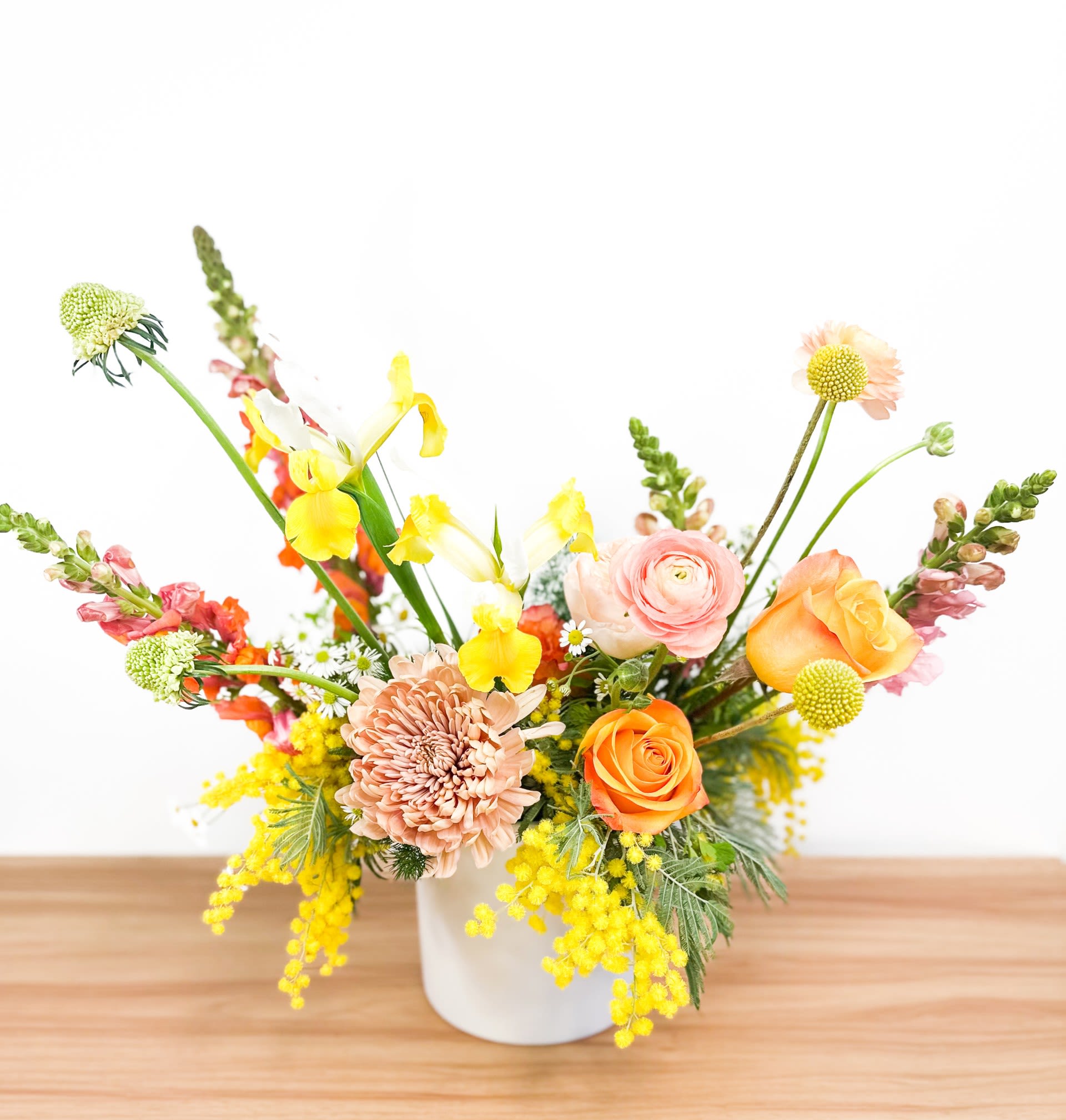 Mixed bouquet in a white vase with orange, pink, and yellow flowers
