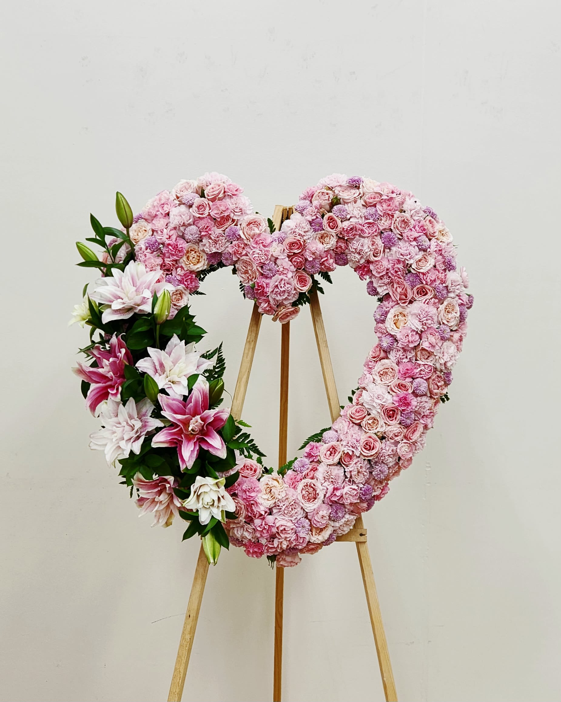 Gentle Heart - A tender expression of love and remembrance, Gentle Heart Spray is beautifully crafted with a soft palette of pink and pastel blooms. At its heart, elegant pink rose lilies open gracefully among delicate roses, carnations, and seasonal blossoms, creating a soothing harmony of color and texture. This design evokes serenity and compassion—an exquisite tribute that whispers comfort and celebrates a life remembered with warmth and grace.  Standard 18" Deluxe 22" Premium: AS PICTURED 30"