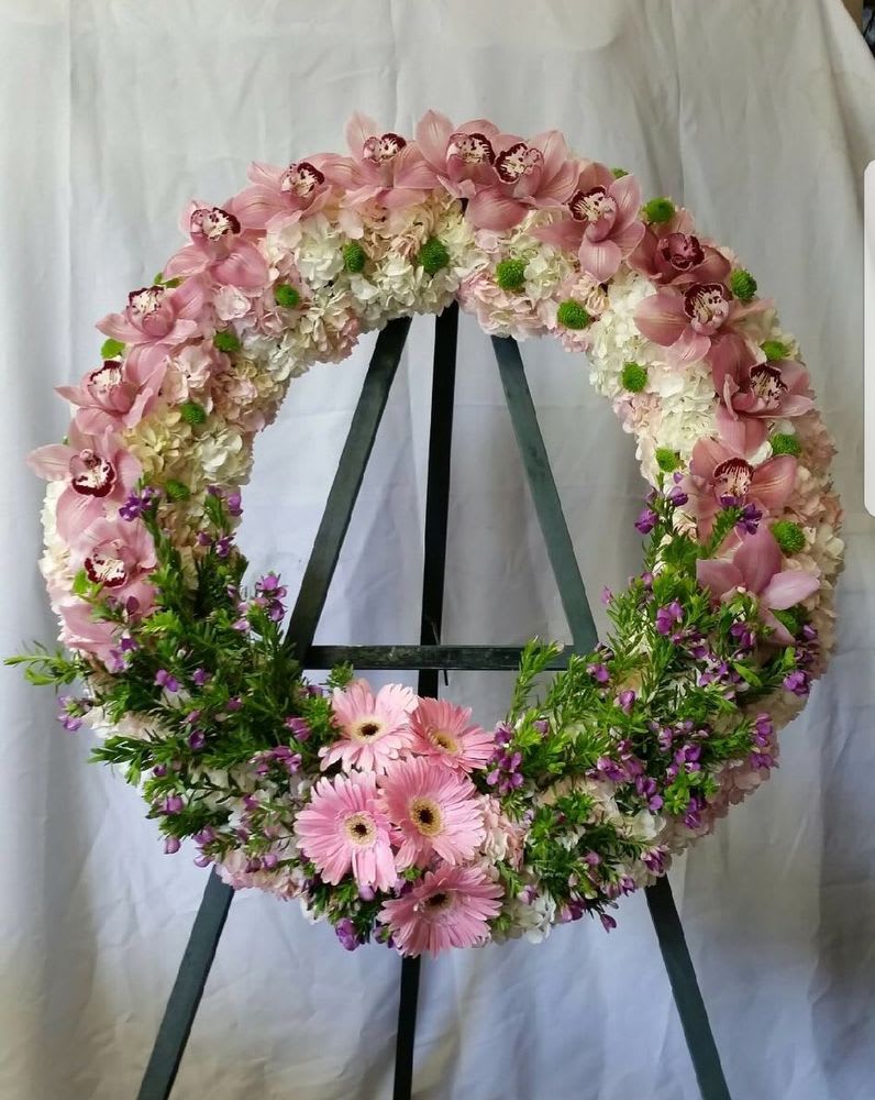Orchids Crown - Honor a cherished memory with this elegant memorial wreath, crafted with premium pink orchids and soft pink gerbera daisies. Each bloom is thoughtfully arranged to create a sophisticated tribute that conveys grace, compassion, and enduring love. Perfect for services, celebrations of life, or expressing heartfelt sympathy. A luxurious choice for those seeking to make a meaningful gesture during difficult times.  ONE SIZE ONLY: 30"
