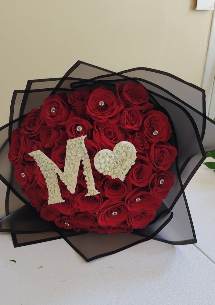 Heart-shaped bouquet of red roses with a white "M" and heart topper