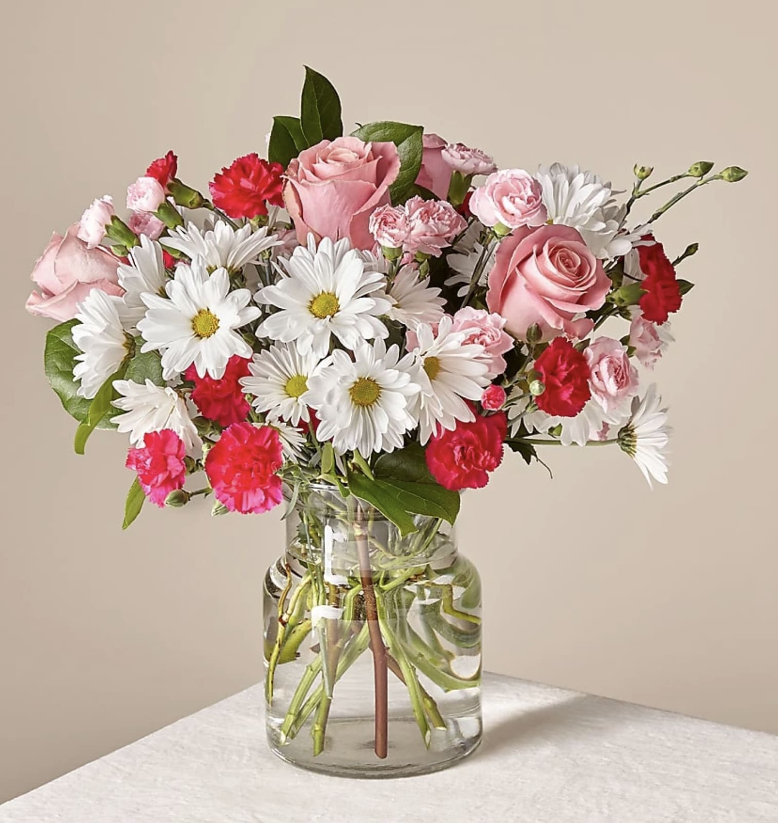 Sweet Surprises Bouquet - The Sweet Surprises® Bouquet was created to spread love and caring kindness wherever it might be sent! Hot pink and pale pink mini carnations pop with their blushing hues, arranged amongst the clean white petals of traditional daisies and lush greens. Presented in a clear glass vase, this gorgeous fresh flower arrangement brings a fresh excitement to your special recipient's day, whether it is sent for a special occasion, such as a birthday, or simply to let them know how much you care.