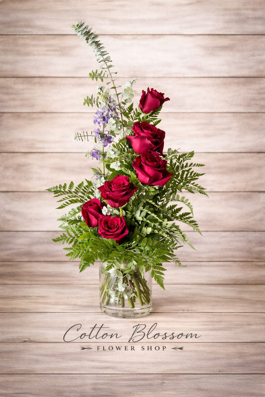 Love to the Heavens - Love to the Heavens – Tower of Red Roses in Maricopa, AZ  Show her just how high your love goes with Love to the Heavens, a striking vertical tower of rich red roses designed to make a lasting impression.  This elegant one-sided arrangement features premium long-stem red roses rising gracefully above lush greenery and soft accent blooms, all beautifully arranged in a clear glass vase. The dramatic height and modern silhouette create a bold, romantic statement perfect for anniversaries, Valentine’s Day, proposals, or any moment when ordinary just won’t do.  Size Options: • Standard – Half dozen red roses • Deluxe – Nine red roses for added height and fullness • Premium – A breathtaking full dozen roses reaching beautifully toward the heavens  Hand-crafted in Cotton Blossom’s signature style using the freshest, highest-quality roses, this arrangement is designed to impress from every angle.  Cotton Blossom Flower Shop proudly offers same-day flower delivery in Maricopa, Casa Grande, and Stanfield, Arizona. Order online today and send a towering expression of love from your trusted local Maricopa florist.