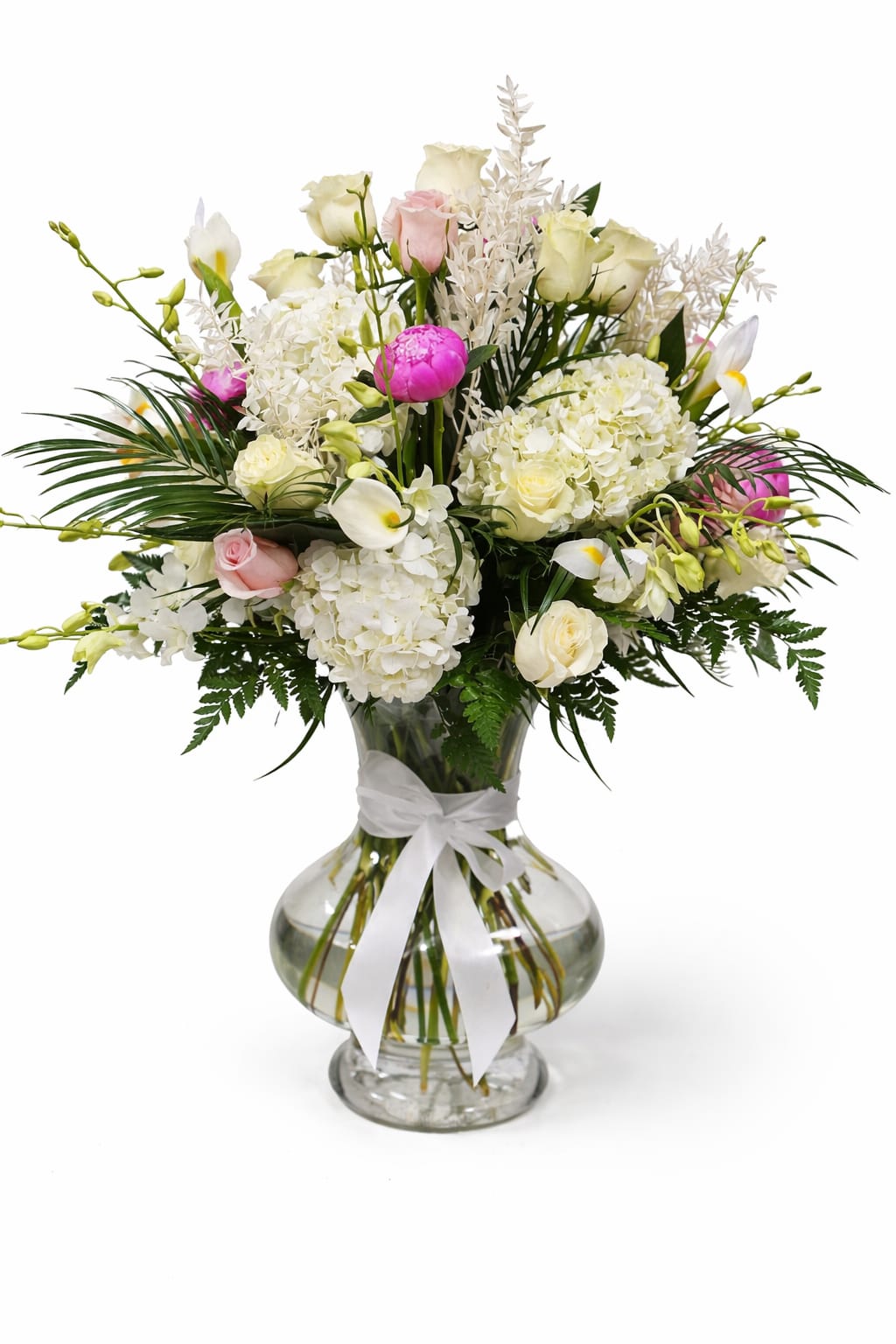 White and pink floral arrangement in a clear glass vase with a white ribbon