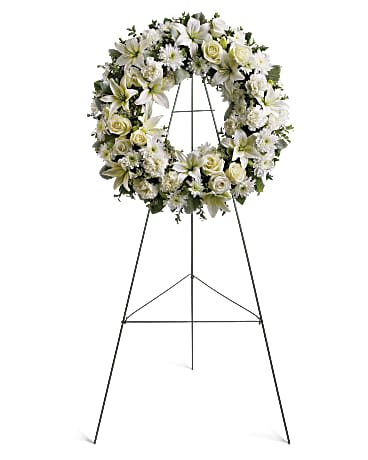 Serenity Wreath - Beautiful mix of white flowers including lilies, roses, pompons, carnations on a round wreath and placed on an easel. Beautiful for a service!