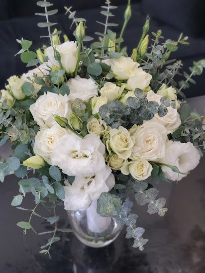 White rose and lisianthus arrangement with eucalyptus in a clear glass vase