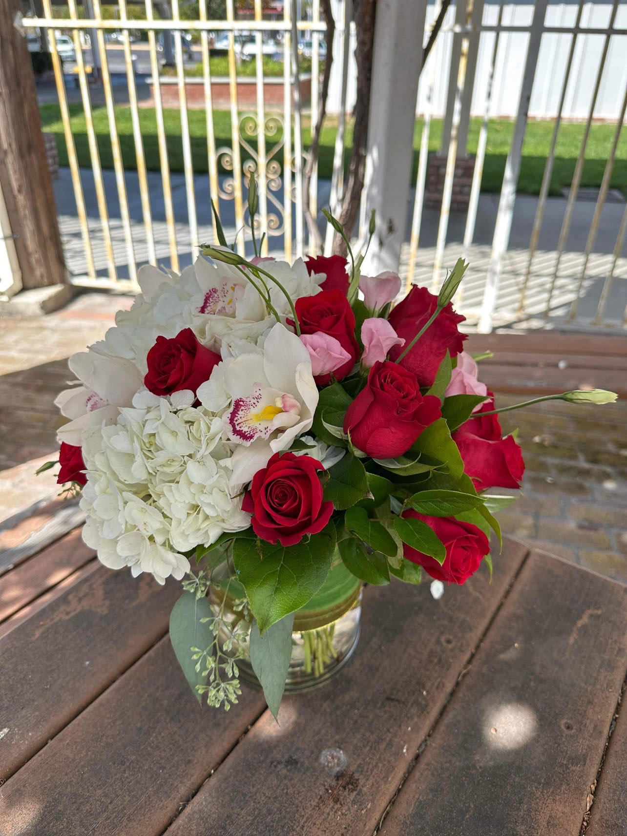 Ladies Day (Red and White) - - 1 White Hydrangea - 6 Red Roses - 5 Pink Lisianthus - 2 Cymbidium Orchirds - 6x6 Inches Cylinder Vase 