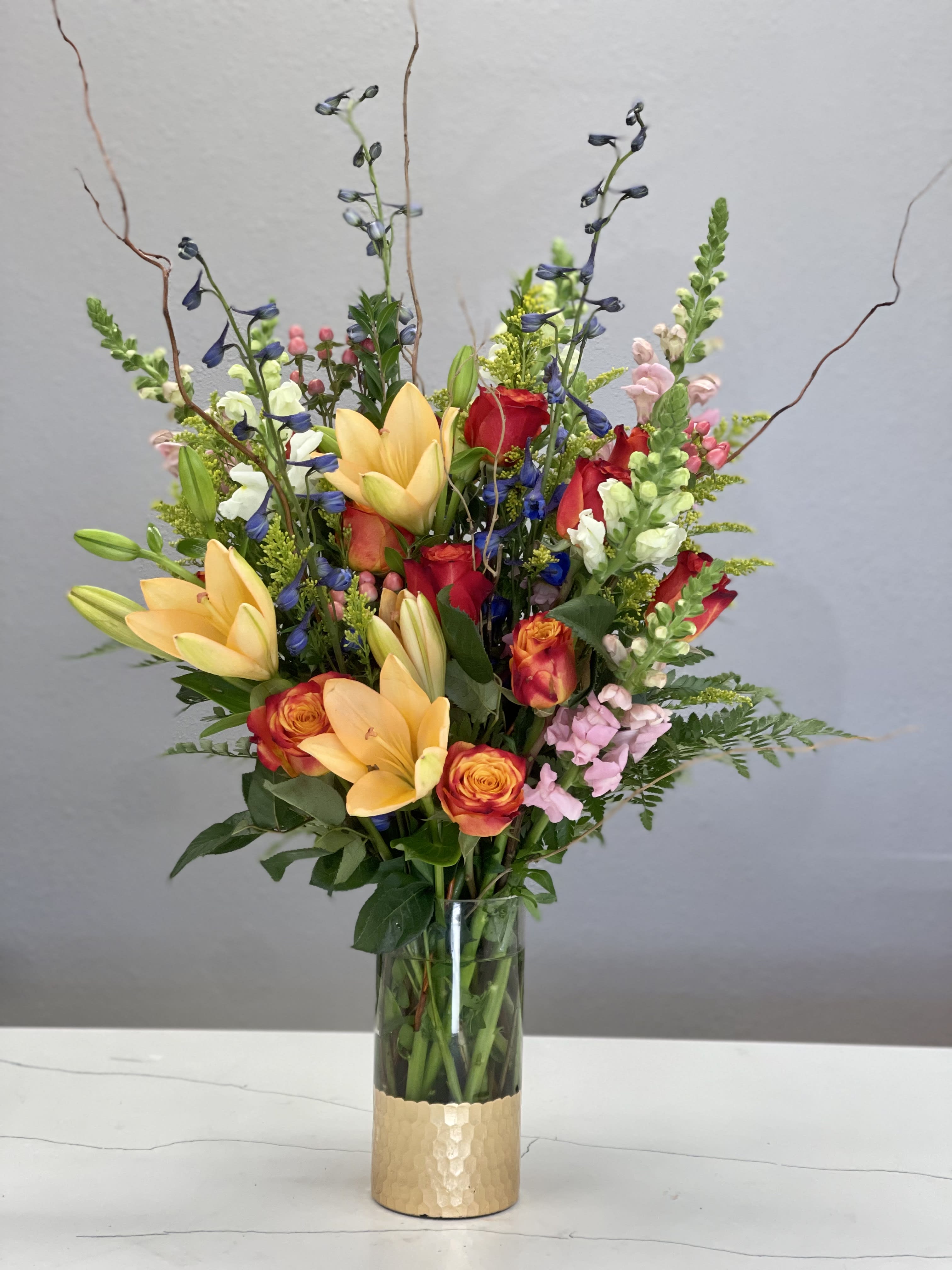 Mamma Mia - Make their day with this bright and vibrant collection of flowers, beautifully presented in a clear/gold glass vase.