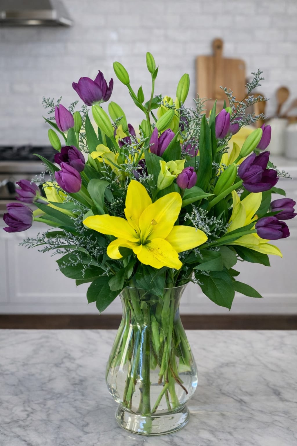 Sunlit Bouquet - This vibrant vaseful is cheerful yet delicate. Lillies and Tulips in a glass vase. A great gift for any happy occasion.     Florist reserves the right to make modifications to the design based on seasonality and accessibility of blooms and vases. Any modifications made will honor the palette, intent, and feeling of the pictured design.