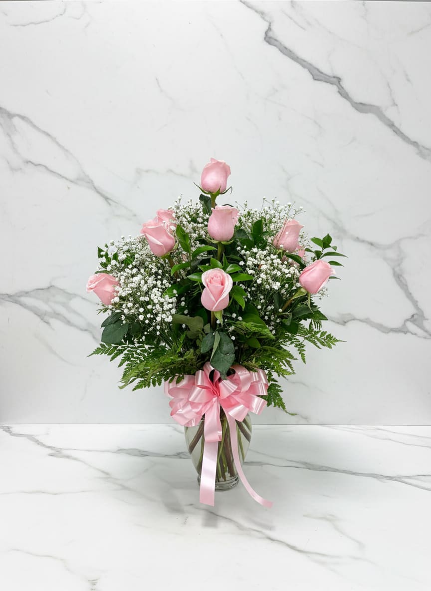 Pink Dozen Vase - Classic pink rose dozen, framed by delicate white baby’s breath, arranged in a clear glass vase and finished with a bold red bow