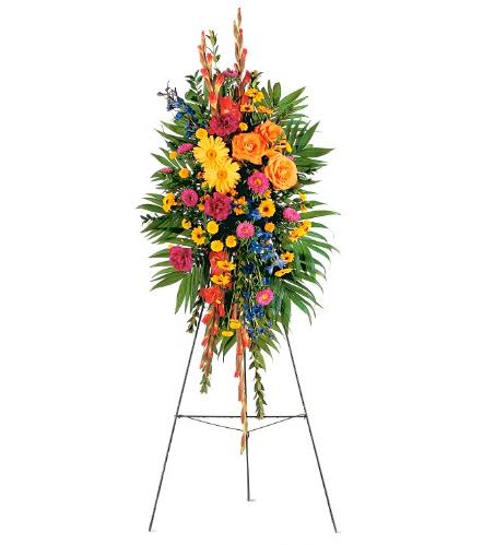 Tall standing spray of bright yellow, orange, pink, and blue flowers on a metal easel