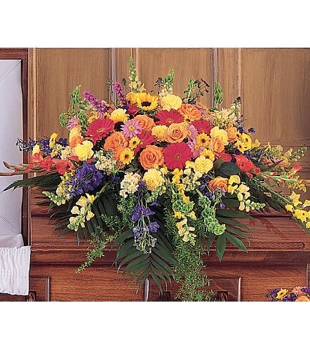 TF203-7  Celebration of Life Casket Spray - The vibrant colors of these flowers celebrate a life filled with joy, compassion and love. One half-couch casket is created using vibrant orange roses and gladioli, sunflowers, purple liatris, yellow snapdragons and red gerberas. Approximately 51" W x 41" H 