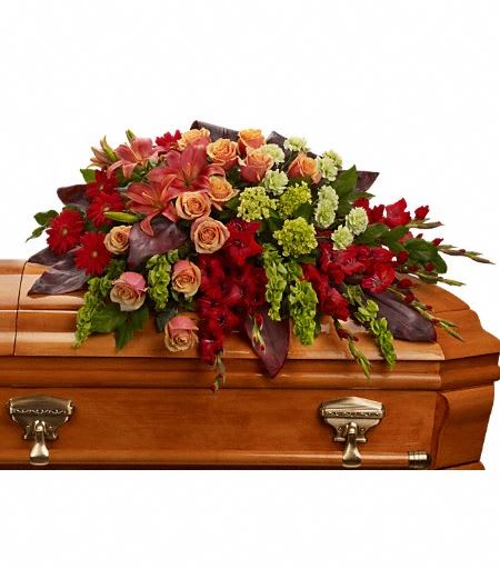 T271-3A  A Fond Farewell Casket Spray - An overflowing of love and respect is joyfully expressed in this truly magnificent casket spray of orange roses and lilies and other brilliant blooms. The magnificent arrangement includes green miniature hydrangea, orange roses, dark orange asiatic lilies, red gerberas, red gladioli, green carnations and bells of Ireland, accented with assorted greenery. Approximately 44" W x 25" H 