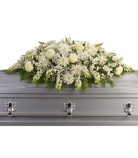Long white funeral casket spray of chrysanthemums and other flowers on a silver casket