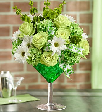 Green Dublin Cocktail - Stir up St. Patrick's Day smiles with our luckiest libation around! Inspired by the popular Irish cocktail, our florists hand-arrange the freshest green carnations, green roses, white poms and Bells of Ireland inside a keepsake oversized martini glass, accented with a festive shamrock ribbon.  Festive green and white arrangement of roses, carnations, poms and Bells of Ireland Hand-designed by our florists in martini filled with green crystal gel 