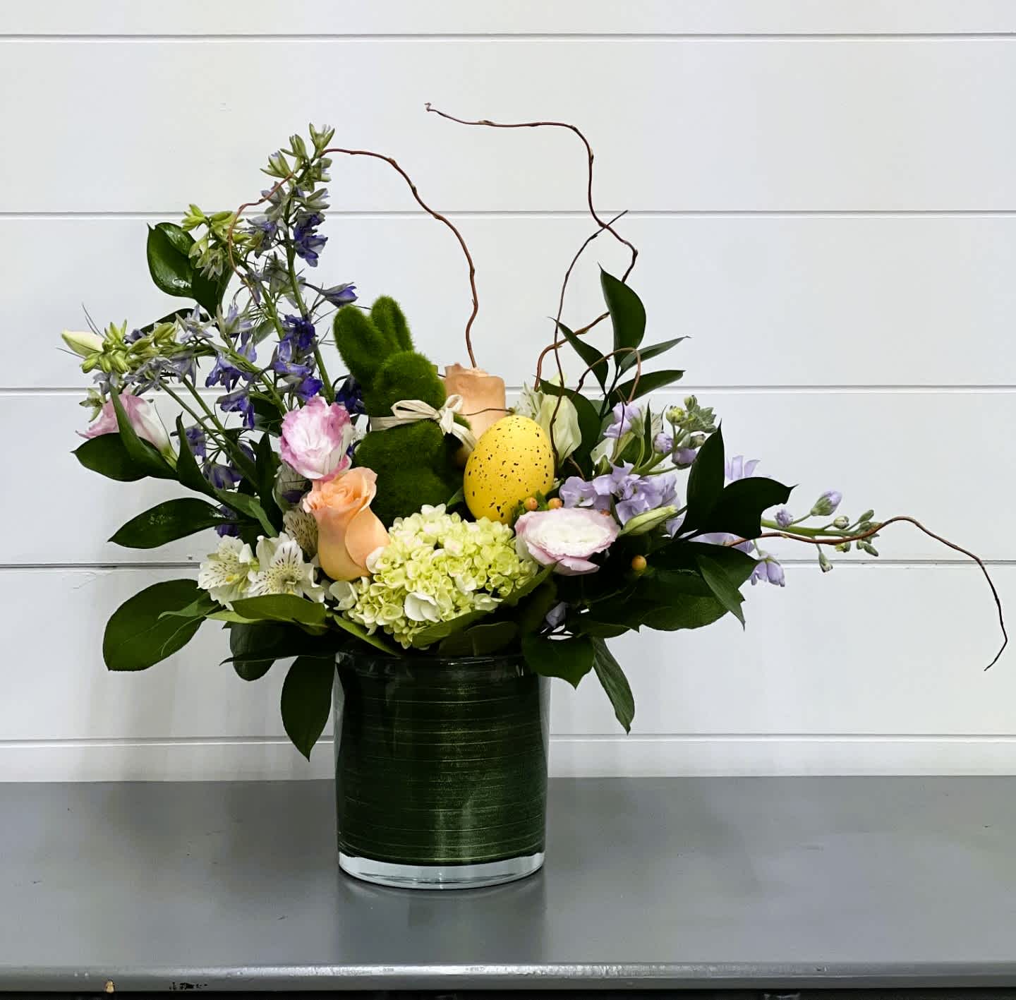 Hippitty Hop Bouquet - Adorn your Easter or Spring table with this festive arrangement filled with beautiful spring flowers and greenery with an adorable moss covered bunny and a colorful Easter egg. 