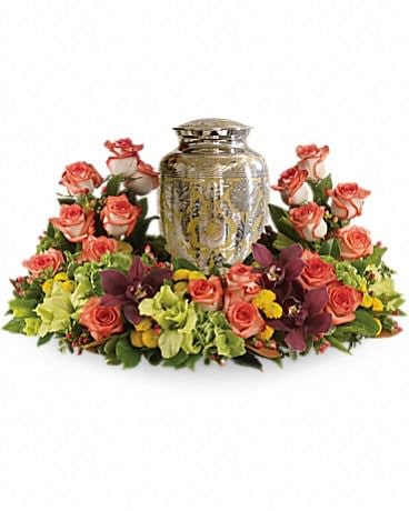 Sunset Wreath - A rich and subtly hued garden expresses sympathy most thoughtfully, in a gentle oval arrangement that honors and embraces a cherished memory. Orange roses blend with other beautiful flowers such as stems of cymbidium orchids, gladioli, chrysanthemums, hypericum and other delicate greens.Please note: Arrangement does not include urn.Approximately 26" W x 16 1/2" H