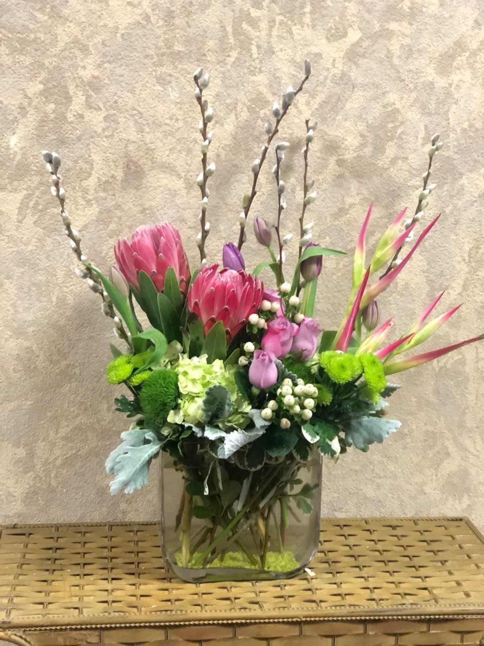 Florida - Type of Flowers: Pink Protea, Lavender Roses,  Green Hydrangea, Lavender Tulips, Pussy Willow, Hypericum Berries, Dusty Miller, and greens in a short vase. Availability: All year round Substitute Available: Yes Design View: Symmetric Front Facing View Photo shown: Regular 