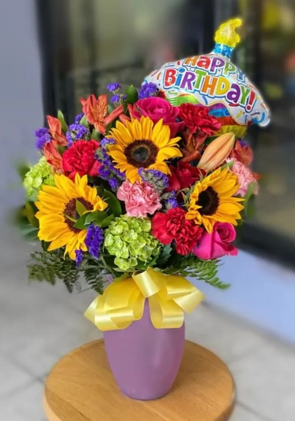 The Birthday Bunch  - Celebrate their special day in a most beautiful way with this burst of bright blooms and a Happy Birthday balloon! This bouquet of roses, sunflowers, alstroemeria, carnations, hydrangea and statice in a pink vase is an extra special birthday surprise!