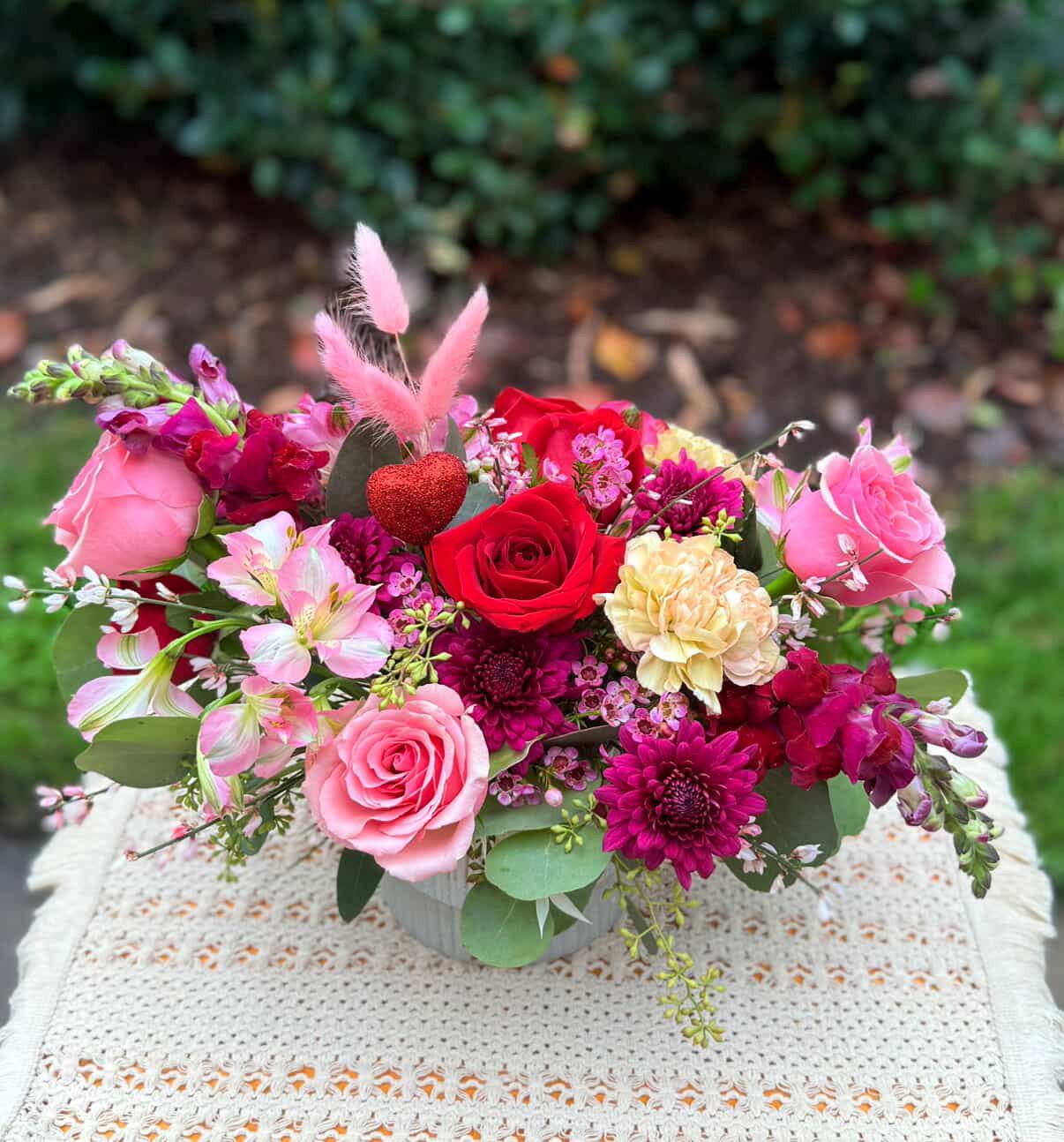 ''Sweet Romance'' Stunning Floral Arrangement - Express your love  with this stunning and romantic garden style arrangement designed with premium flowers: Ecuadorian roses, fancy carnations, alstromerias, cushion pompom, snapdragons, seasonal foliage, fragrant wax flowers, accented with a lovely red heart. It includes  a beautiful ceramic vase in soft white color. Medium size Tones: red,  burgundy, pink and peach tones . It includes a greeting  card to write your message. Note: please read the substitution policy 