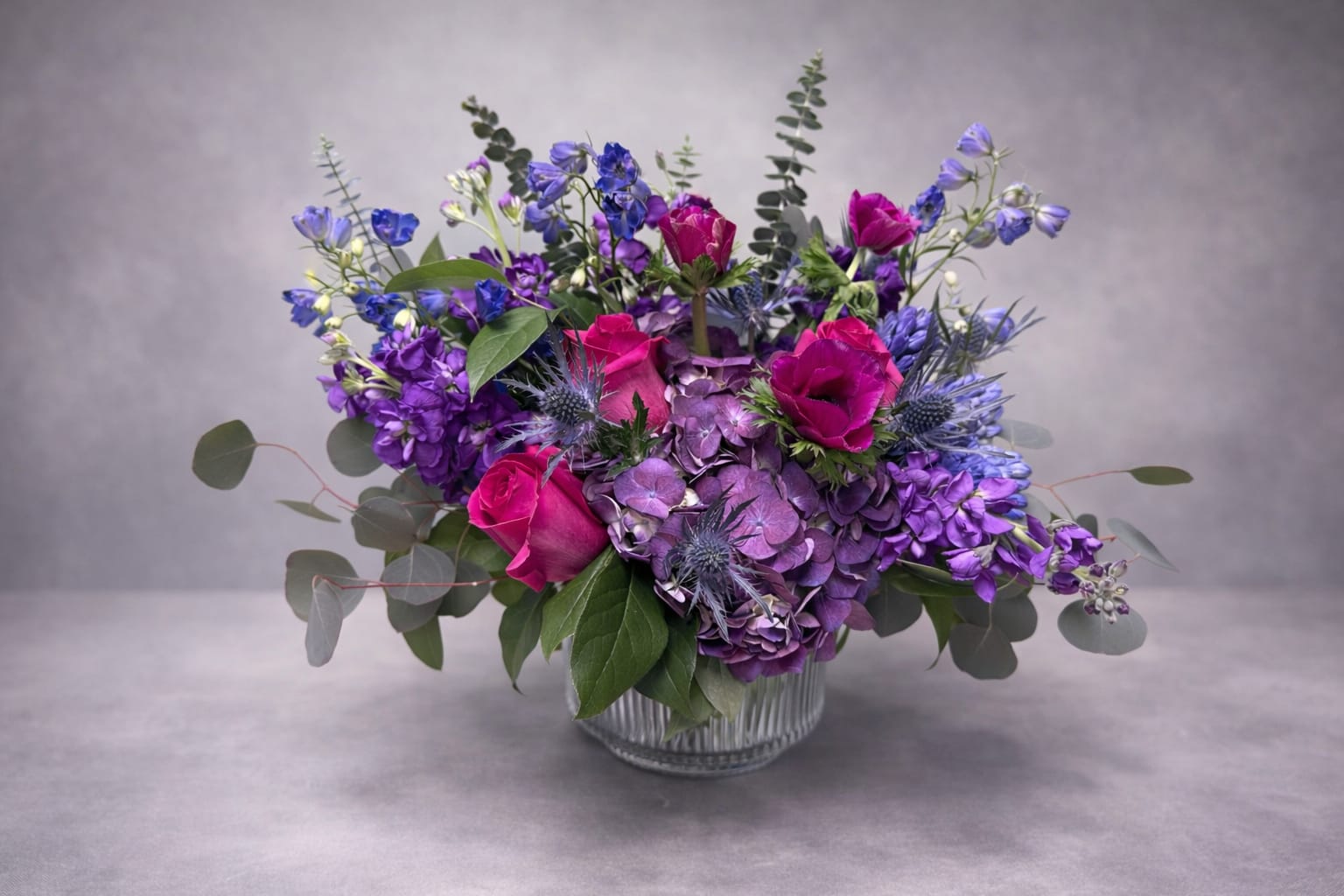 Purple and pink floral arrangement in a clear glass vase