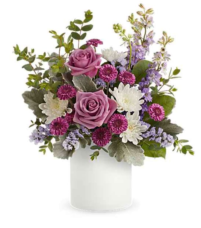 Playfully Yours Bouquet - A playful spin on the classic rose bouquet, these lovely lavender blooms look fun and flirty in this frosted white glass jar. Lavender roses, purple button spray chrysanthemums, white cushion spray chrysanthemums, lavender larkspur and lavender sinuata statice are arranged with dusty miller, parvifolia eucalyptus and lemon leaf. Delivered in Teleflora's Savannah Jar. Orientation: All-Around