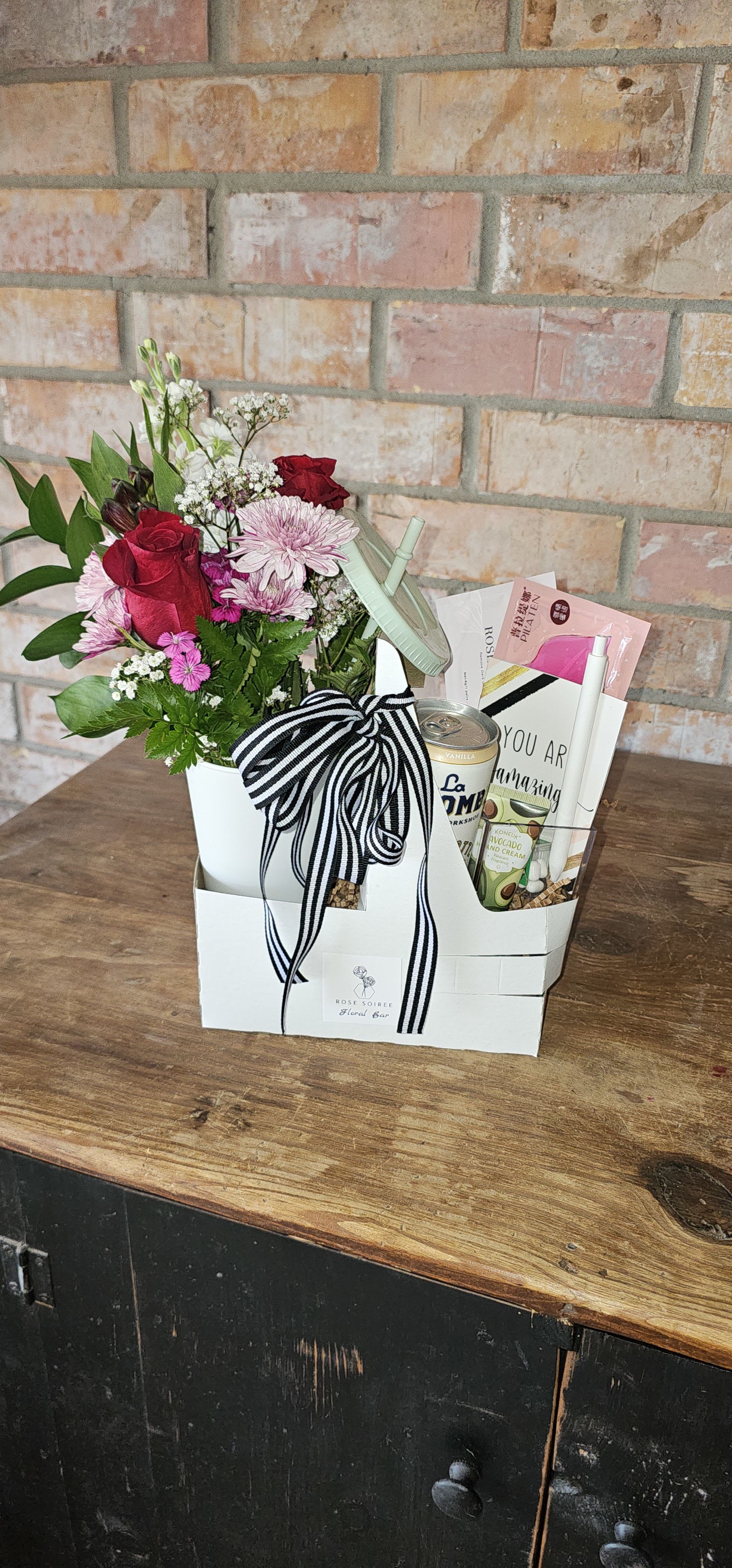 The Bloom Break  - A cheerful mix of fresh florals, a light sip, and feel-good treats — perfect for office birthdays and everyday wins. The perfect little “pick-me-up” for any occasion.  Designer’s choice florals Paired with a canned latte or iced coffee , or energy drink. (drinks may vary) Great for “Thanks a latte,” “I love you a latte,” or even a sweet treat!  Includes: Designer Choice mini bouquet in a  Keepsake tumbler with straw and lid Carrier Drink (Alani, or Iced Coffee, please specify a preference) Sweet and savory Treat Mini notebook Pen 