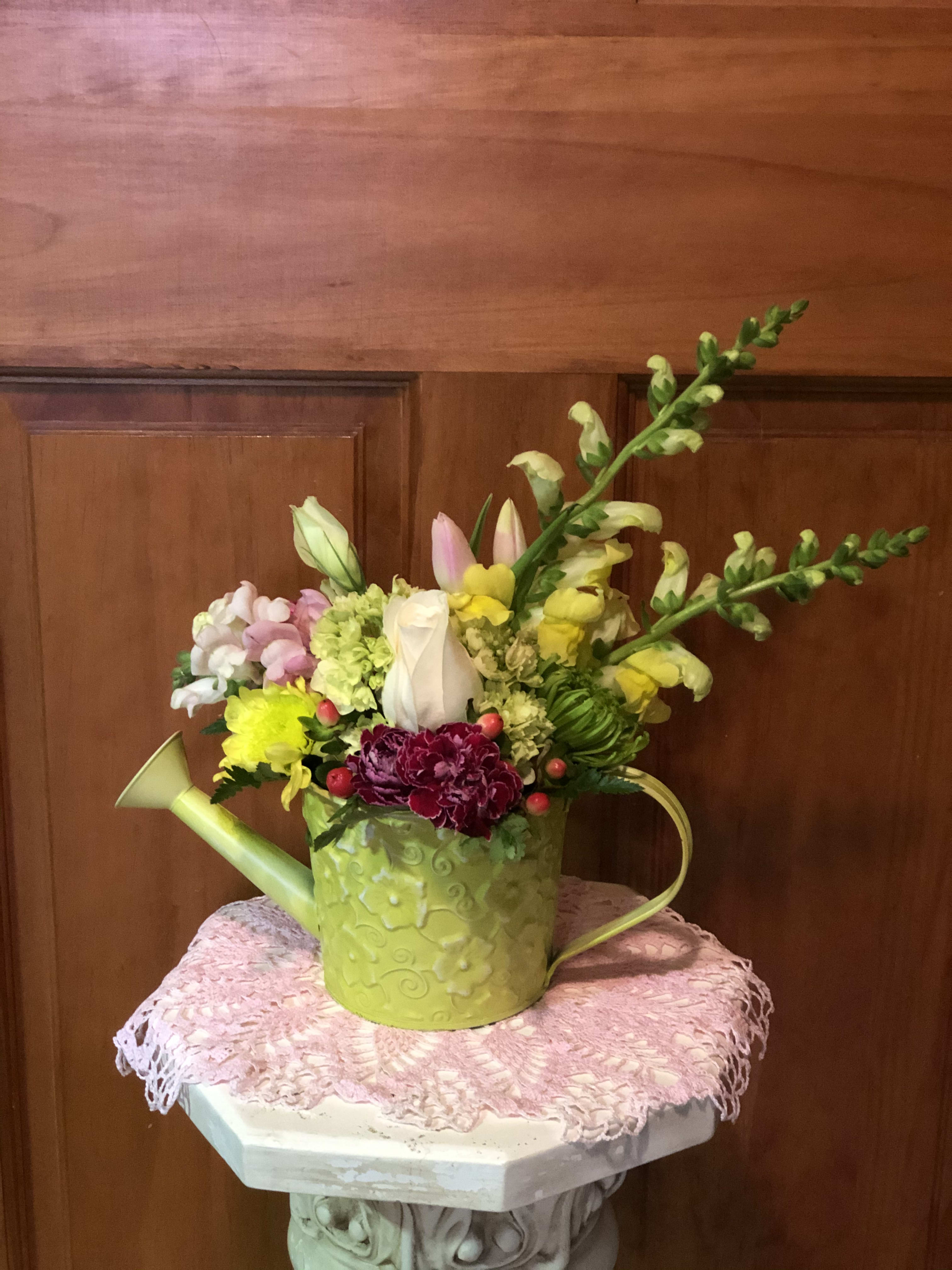 Mixed flowers arranged in a green watering can
