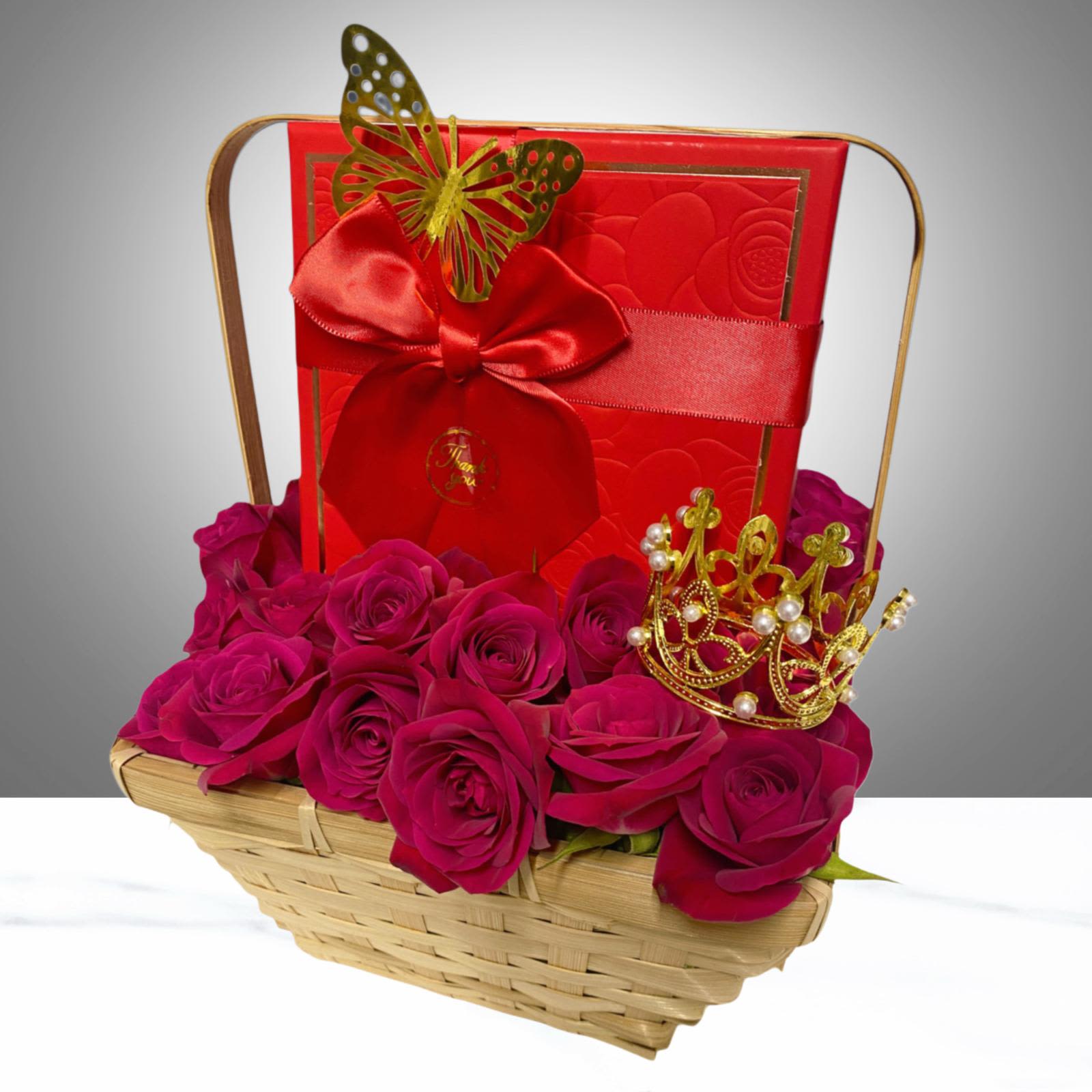 A crown for her - Mini rose garden arranged in a natural basket measuring 9 inches long by 11 inches high.  It includes a medium-sized box filled with delicious, imported chocolates, a decorative butterfly, a message card, and a small golden crown placed above the roses for an elegant touch.  