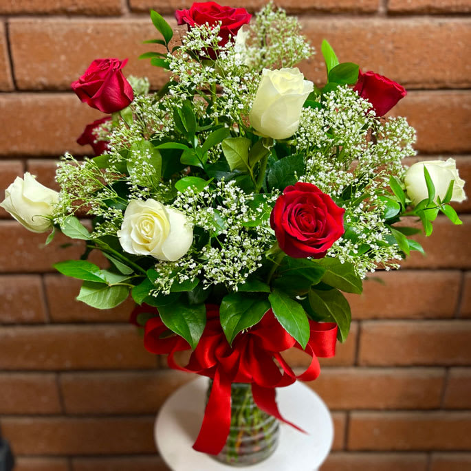 Long Stem Red and White Roses Vase - Long Stem Red and White Roses Vase  Celebrate love in its purest form with our stunning Long Stem Red and White Roses Vase. Featuring premium Ecuadorian long-stem roses in timeless red and elegant white, this arrangement is the perfect symbol of romance, admiration, and devotion. Accented with delicate Baby’s Breath (Gypsophila) and lush garden greens, each bouquet is hand-designed in a clear glass vase and finished with a decorative bow. Available for same-day rose delivery in San Diego, it’s a gift that makes every occasion unforgettable.  Size Options:  • Standard – One Dozen (12) Long-Stem Red &amp; White Roses with fresh greens and fillers in a clear glass vase.  • Deluxe – Two Dozen (24) Long-Stem Red &amp; White Roses with additional greens and fillers in a larger vase for a fuller look.  • Premium – Three Dozen (36) Long-Stem Red &amp; White Roses with abundant greenery and fillers in an oversized glass vase for the ultimate show-stopping display.  Approximate Size (Standard): 20" W x 28" H  Care Tips:  • Display your bouquet in a cool location away from direct sunlight, heat, or drafts.  • Keep the vase filled with clean water and refresh it every 2–3 days.  • Trim stems at an angle when changing the water to help roses absorb nutrients.  • Remove any fading petals to maintain freshness and beauty.
