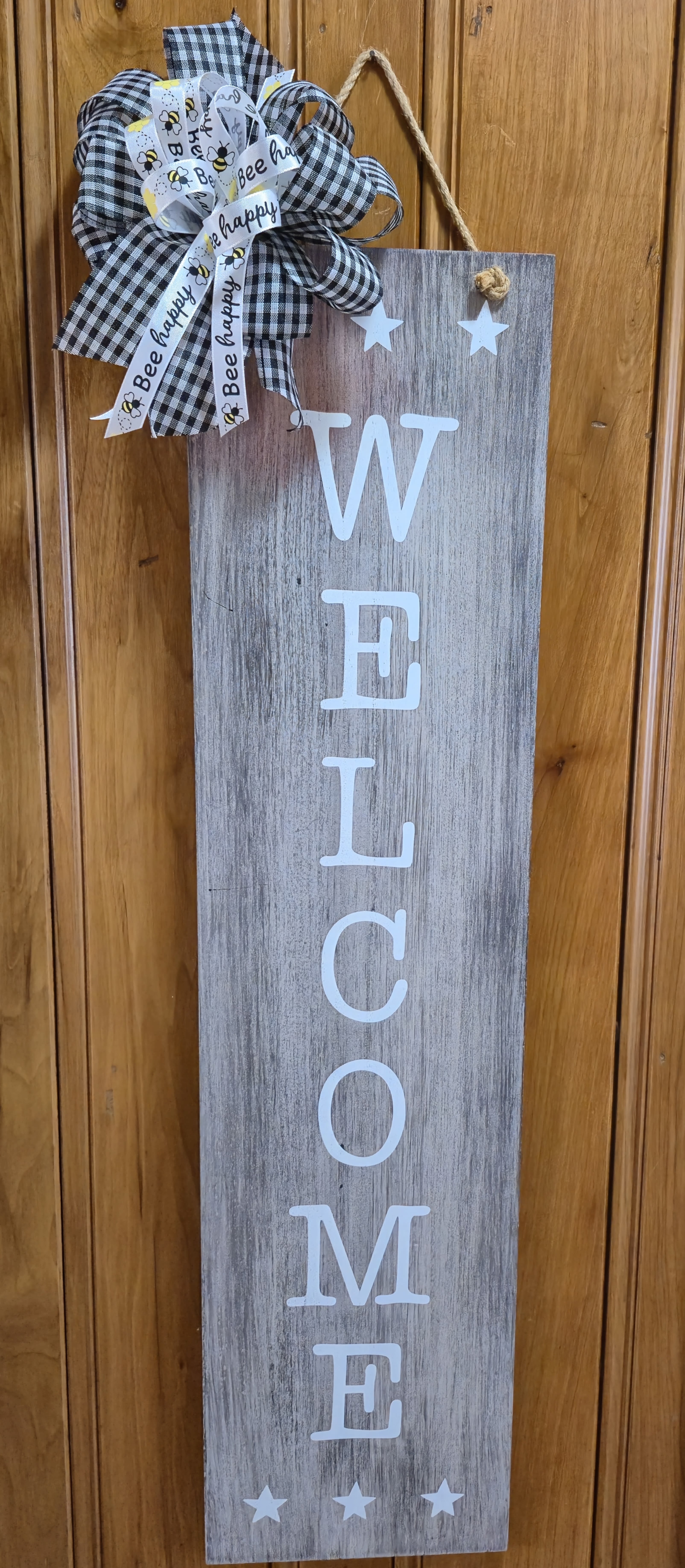 Bee Happy Wood Welcome Sign  - Reversible wall hanging or porch sitter. One side has distressed wood look with "Welcome" message down the center and stars at top and bottom. Side two is a distressed red and white stripe flag with a galvanized star at top.  Hand painted with galvanized tin star.  32"H x 8"W. 35"H hanging.