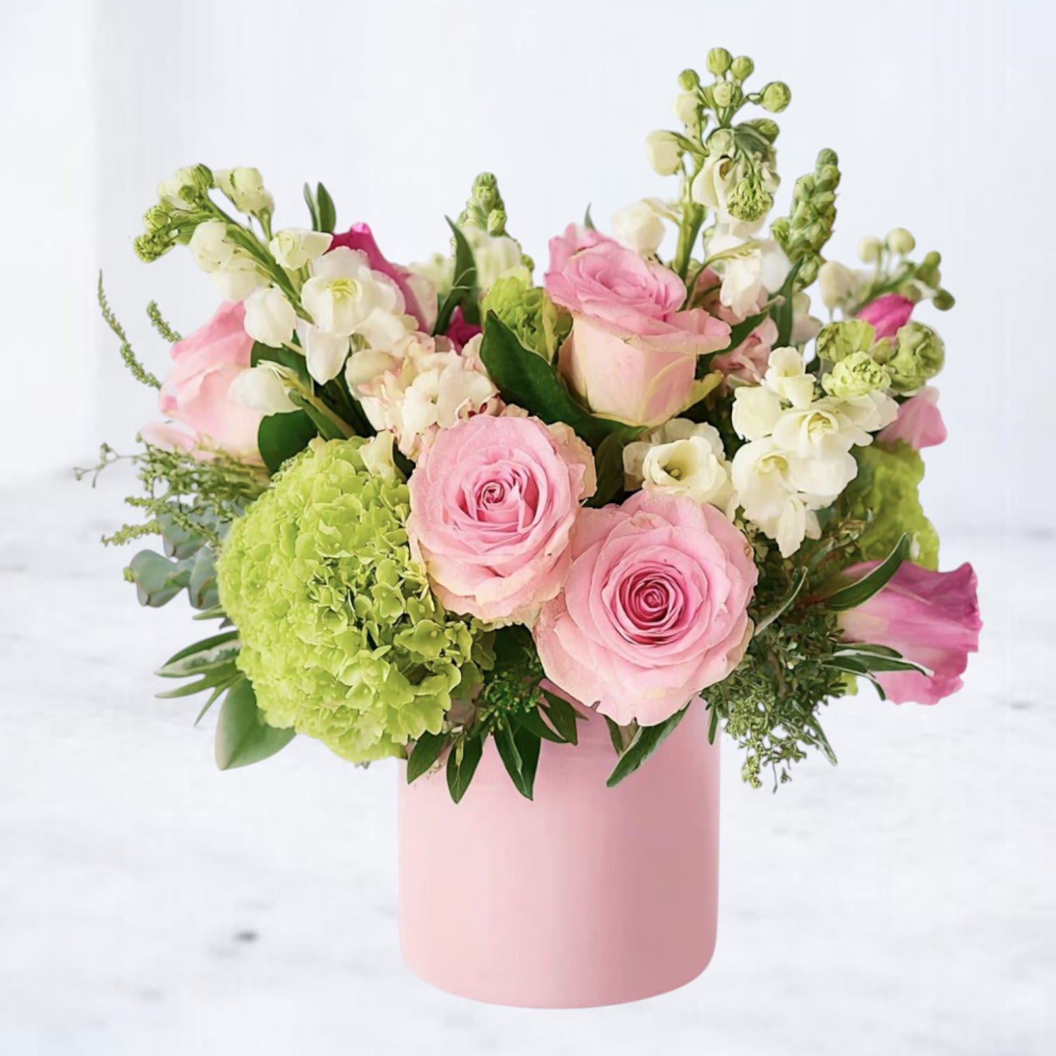 Pink Lemonade - Bring a splash of joy to any occasion with Pink Lemonade — a cheerful and refreshing arrangement that blends the sweetness of blush roses, creamy stock, and lime-green hydrangeas with playful accents of peach snapdragons and hypericum berries. Hand-designed in a soft pink vase, it’s a modern floral delight bursting with energy and springtime magic.  Whether you're celebrating a birthday, welcoming a new baby, or simply making someone’s day a little brighter, this bouquet delivers happiness in every petal.