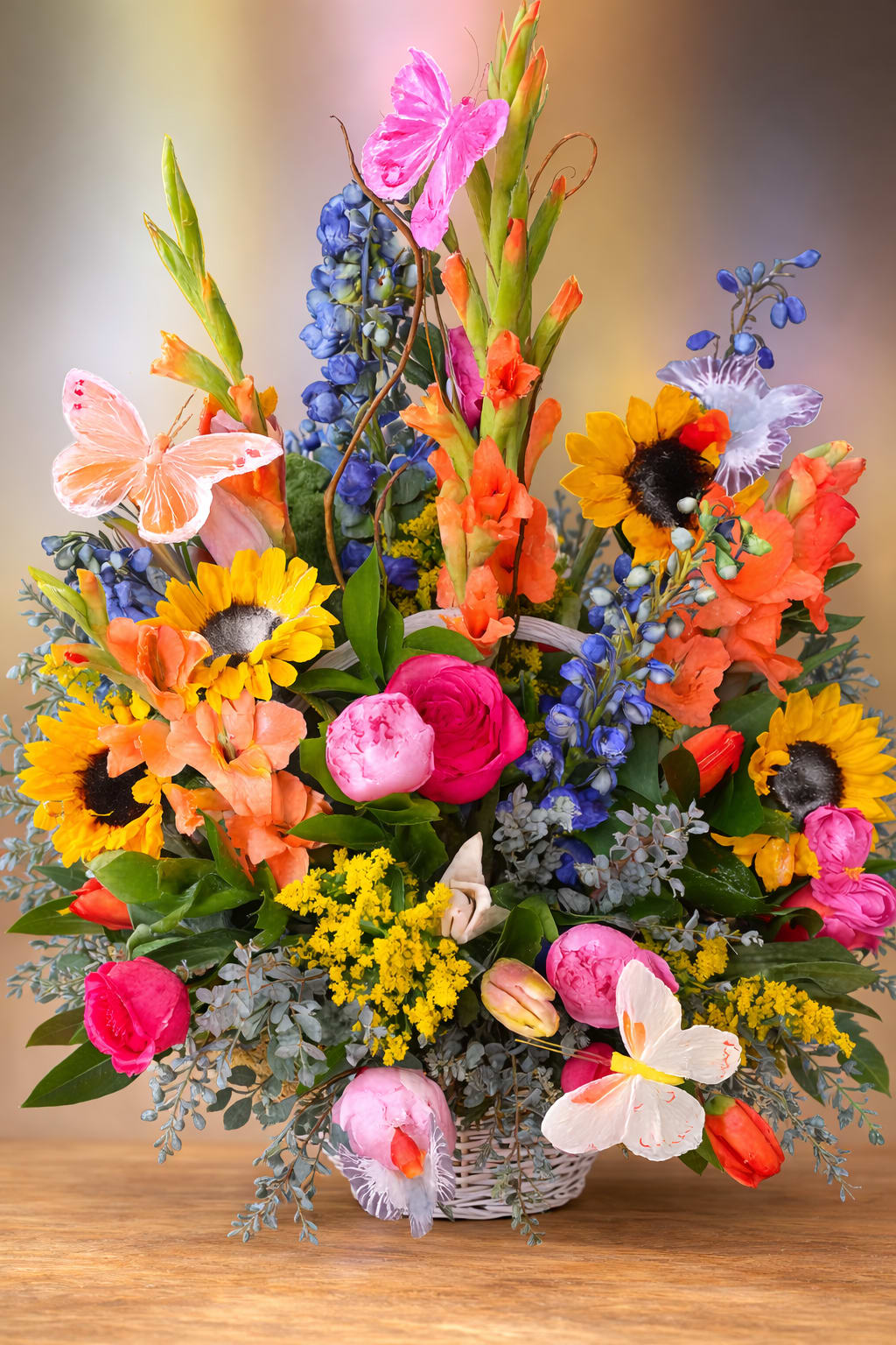 Whimsical Butterfly Garden Basket  - Blue delphinium, sunflowers, peonies, roses, tulips, glads, lilies, solidago, butterflies and assorted greens arranged in a wicker basket 