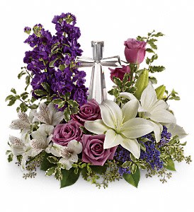  Grace And Majesty Bouquet - A bouquet to remember. This glorious garden of roses, lilies and alstroemeria surrounds a gleaming Crystal Cross. It's a radiant, reverent expression of faith that will be appreciated for years to come. Lavender roses, white asiatic lilies, white alstroemeria, purple stock and purple seafoam statice are arranged with fresh pitta negra, seeded eucalyptus and lemon leaf. Delivered with a Crystal Cross keepsake. Approximately 16 1/2" W x 14 3/4" H