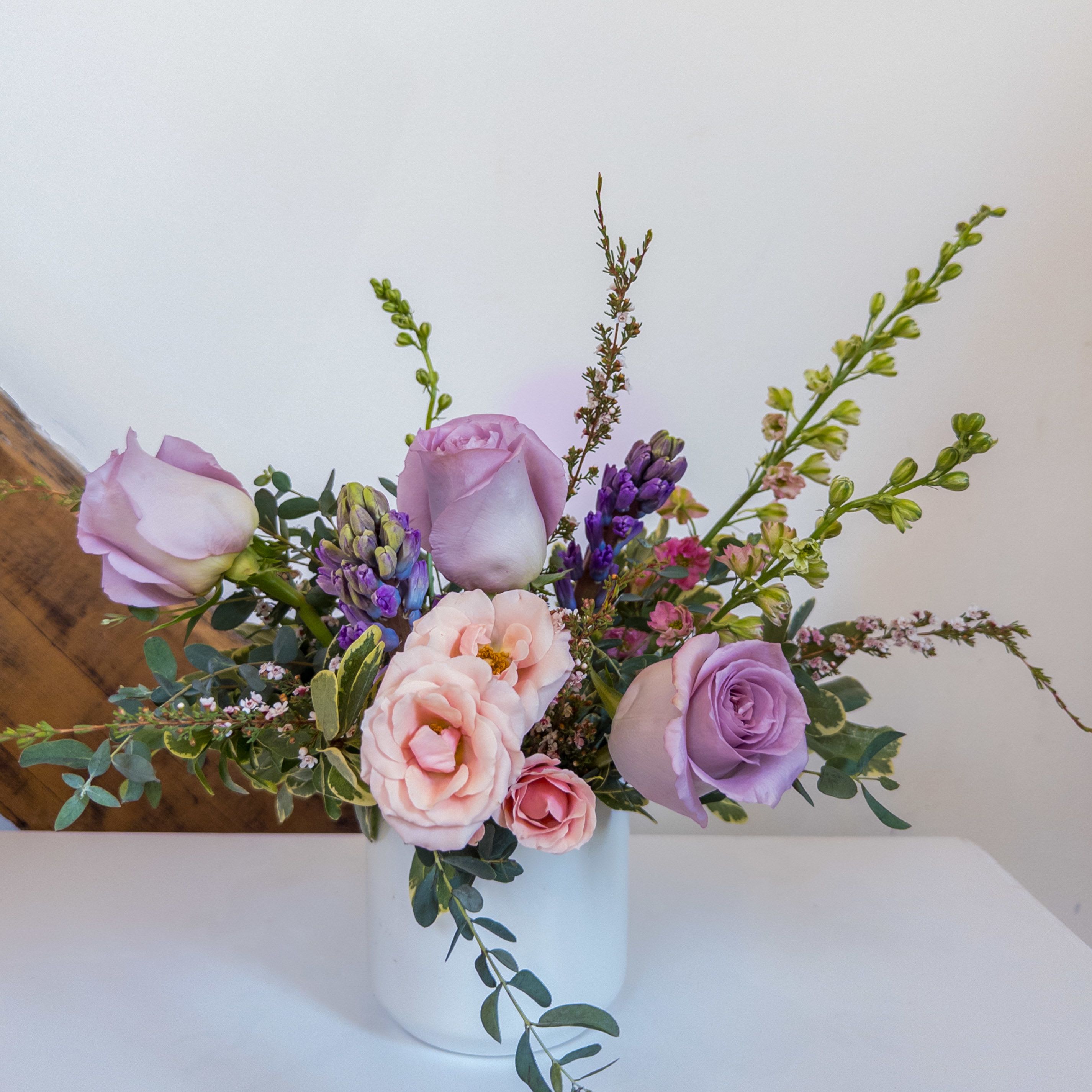 Dewdrop Duet - A sweet and feminine blend of spring lavenders and pinks designed in our classic white ceramic vessel. Measuring approximately 10x10. Upgrade to deluxe and premium for additonal blooms.