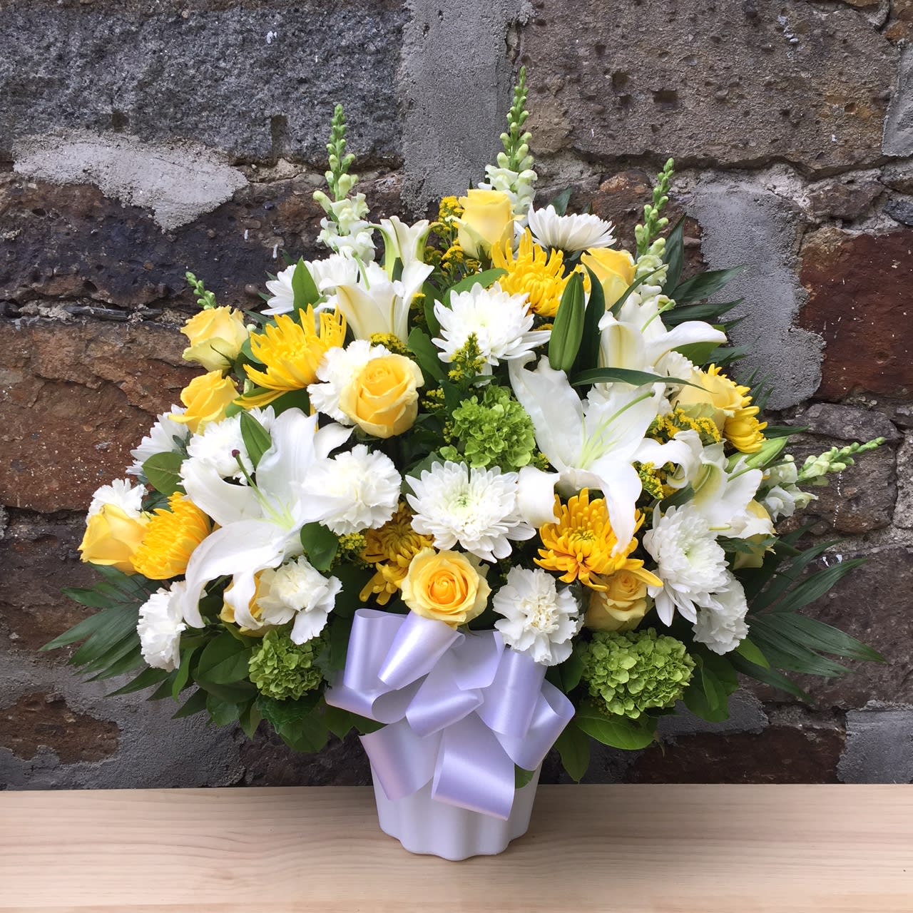 Citrus Urn - Yellow, green, and white flowers  Coordinates with Citrus Casket Spray for a full set.   Call for a package of 2 Citrus Urn and 1 Citrus Casket Spray for $450 (save $50). 