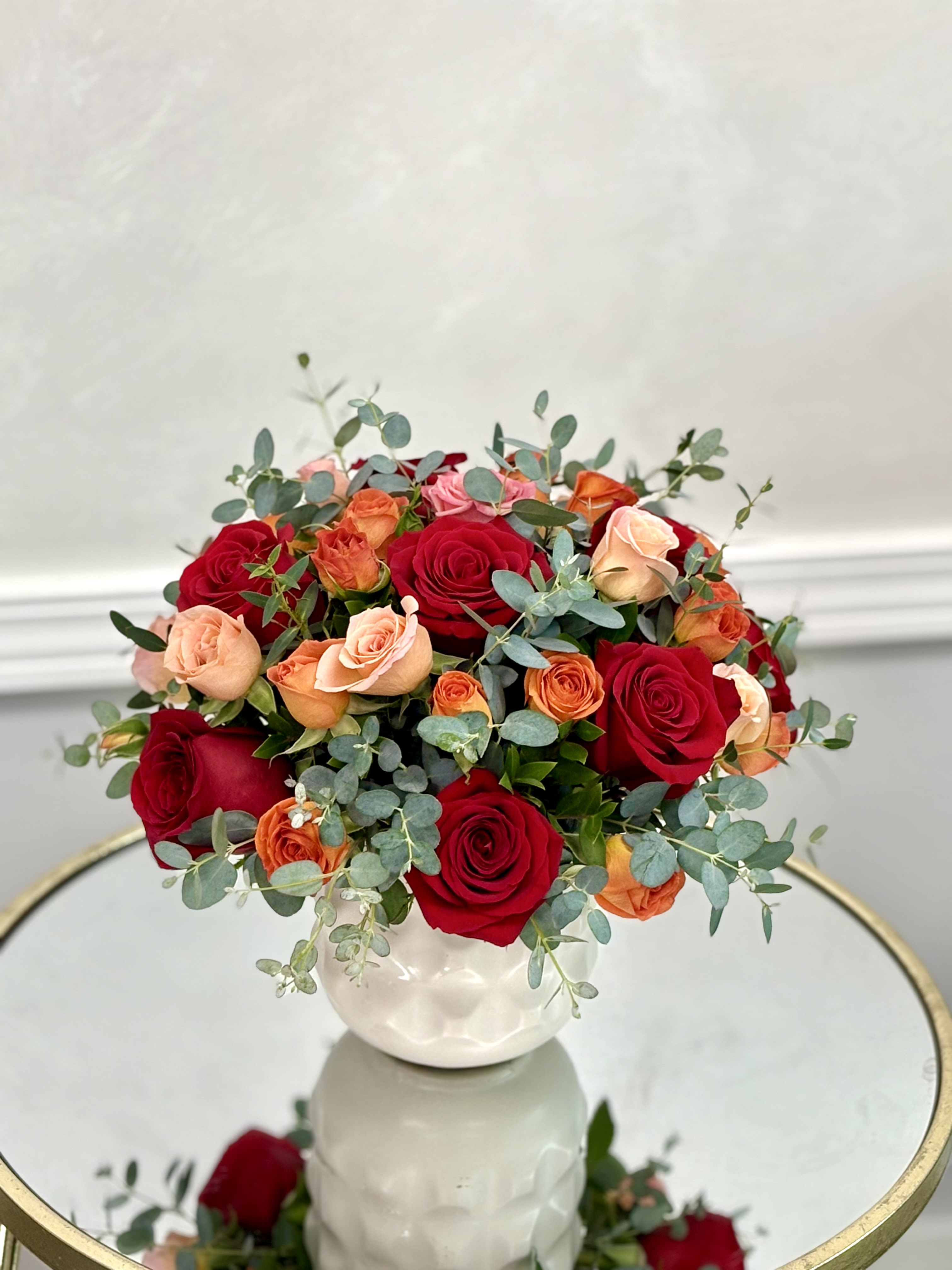 Bouquet of red and peach roses in a white vase