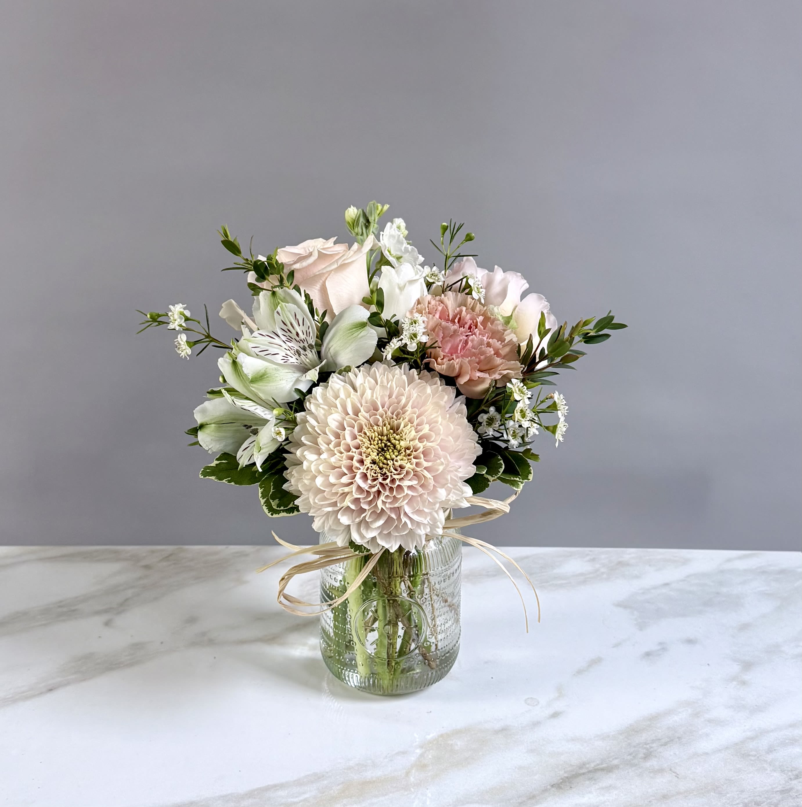 Soft Colored Seasonal Mix- Size small  - A small jar filled with our weekly seasonal mix of soft colors. A blush cremon, rose, carnation, spray rose, white stock, tulip and alstroemeria make up this small and pretty arrangement. 
