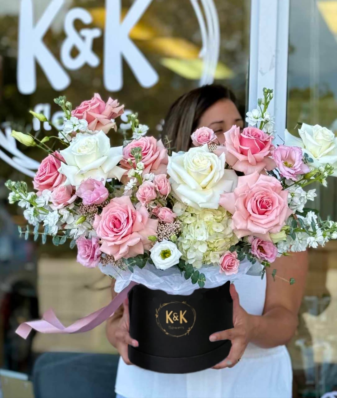 Large pink and white rose arrangement in a black hat box
