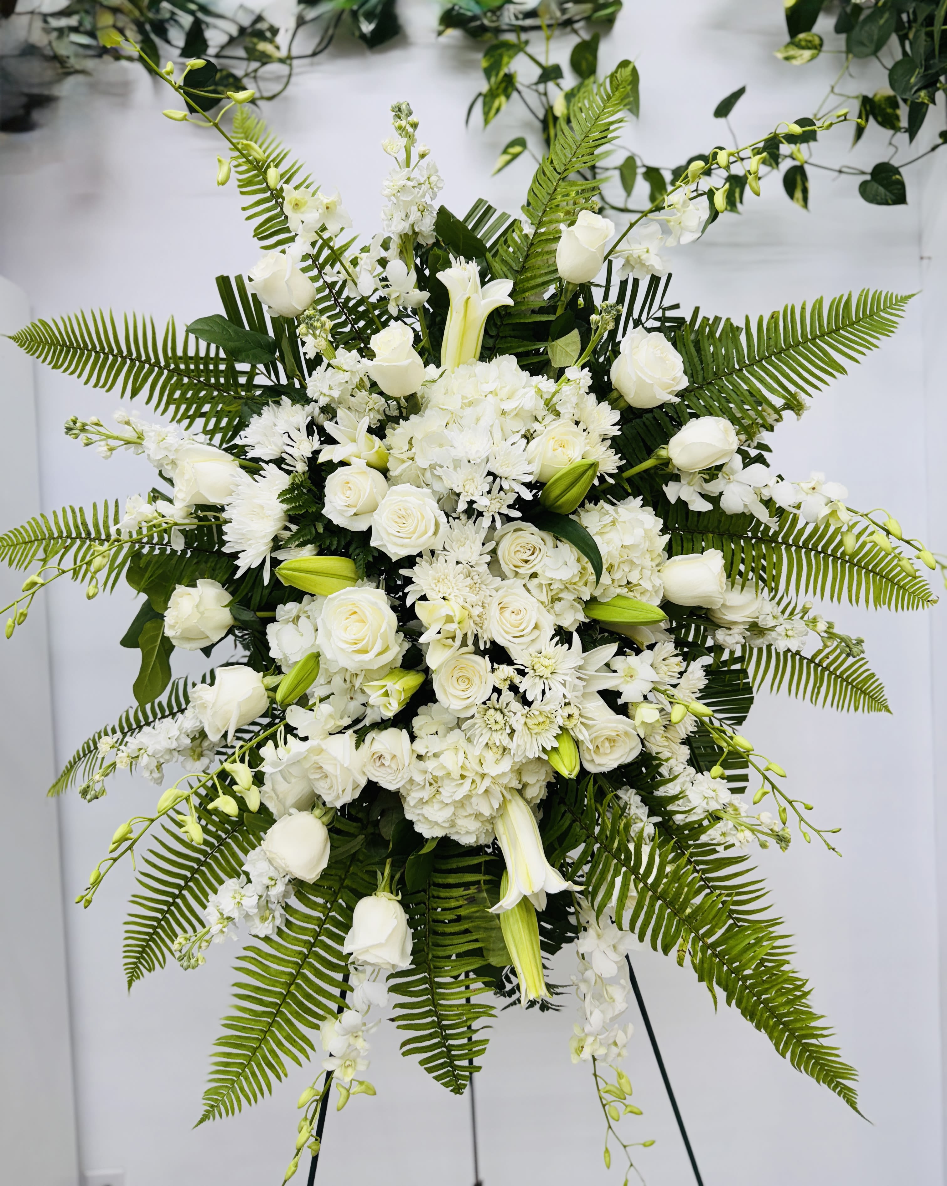 White True Sympathy  (Spray) - An all white tribute, this funeral spray is pure and tranquil. Featuring a variety of white flowers and green palms this elegant funeral spray brings a feeling of peace to it's surroundings 