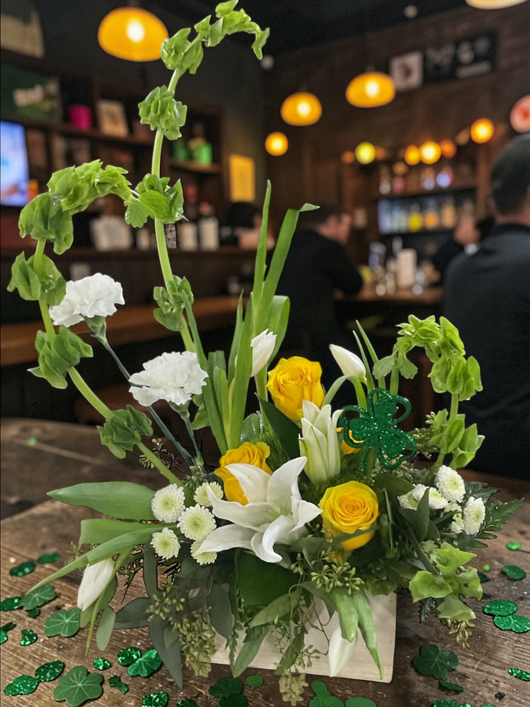 Luck of the Irish - Celebrate St. Patrick’s Day with Luck of the Irish, a fresh, uplifting blend of Bells of Ireland, white lilies, sunny yellow roses, and crisp seasonal greens. Designed to feel bright, natural, and full of movement, this arrangement brings the spirit of the holiday to life with a modern studio style.  Perfect for home décor, office displays, parties, or sending a burst of St. Paddy’s cheer. Hand-crafted in our studio with premium blooms and photographed exactly as arranged..