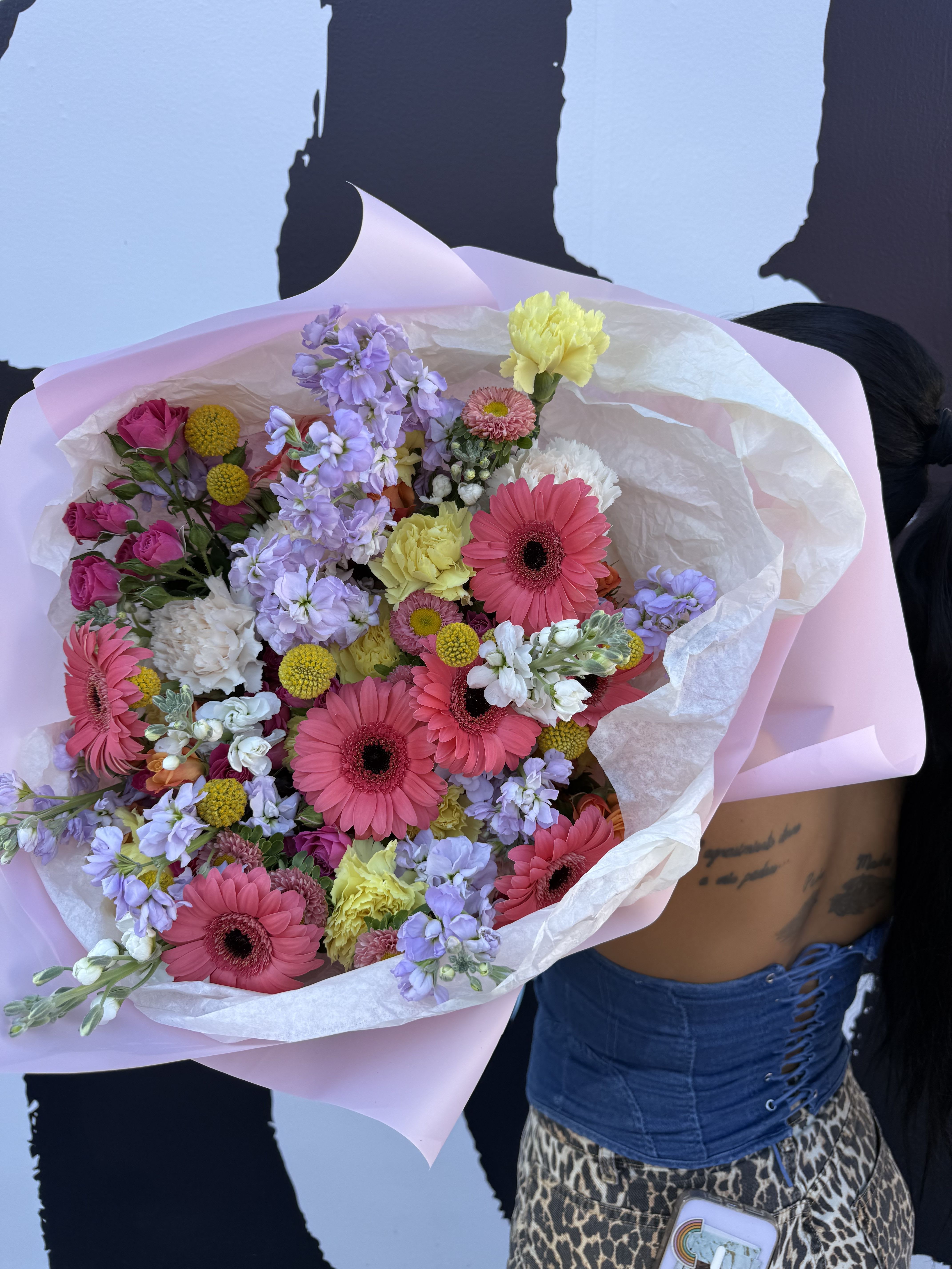 Garden Serenade - Garden Serenade is a joyful celebration of color and texture, inspired by the beauty of a blooming spring garden. This vibrant bouquet features bold pink gerbera daisies paired with soft lavender stock, cheerful yellow carnations, delicate white snapdragons, and clusters of charming pink spray roses. 