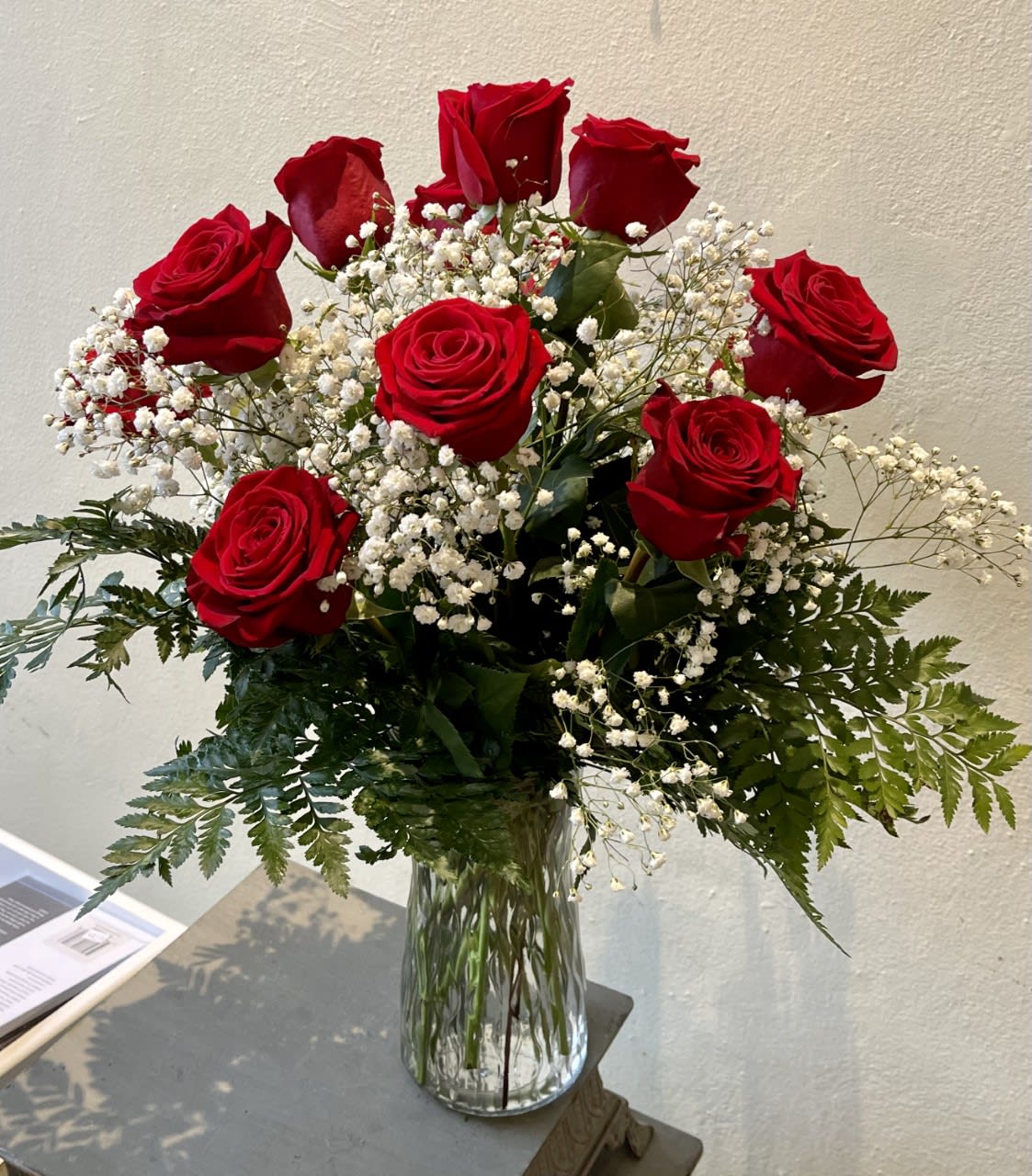 One Dozen Roses - The Posies by Patti one dozen roses pictured features 12 red roses, babies breath, and greenery in a clear vase. 