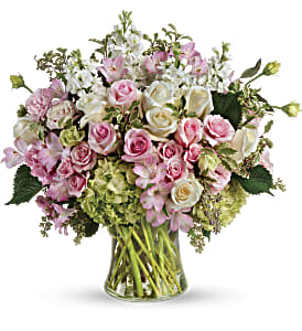 Pink and white roses arranged in a clear glass vase