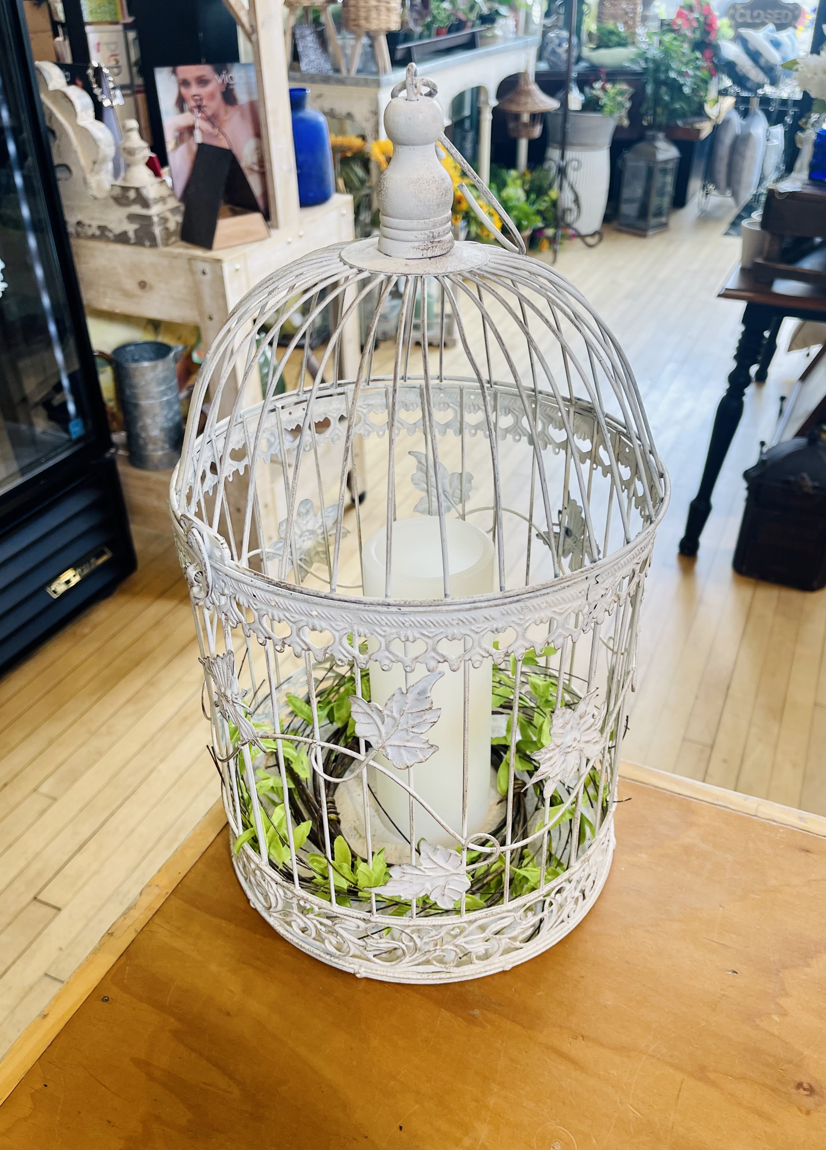 Large Bird Cage Lantern - Want something different? Have a fellow bird lover? This is perfect for someone looking to purchase out of the ordinary. This white lantern consists of a glass free look with a candle and wreath included inside. Approximately 17 inches tall.