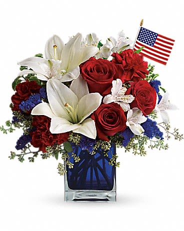 America the Beautiful  - This patriotic arrangement is such a stunning way to honor the courage, the character, the people and the places in this country we call home. Red roses and carnations, white asiatic lilies and alstroemeria, blue statice and an American flag fill an exclusive blue glass cube.