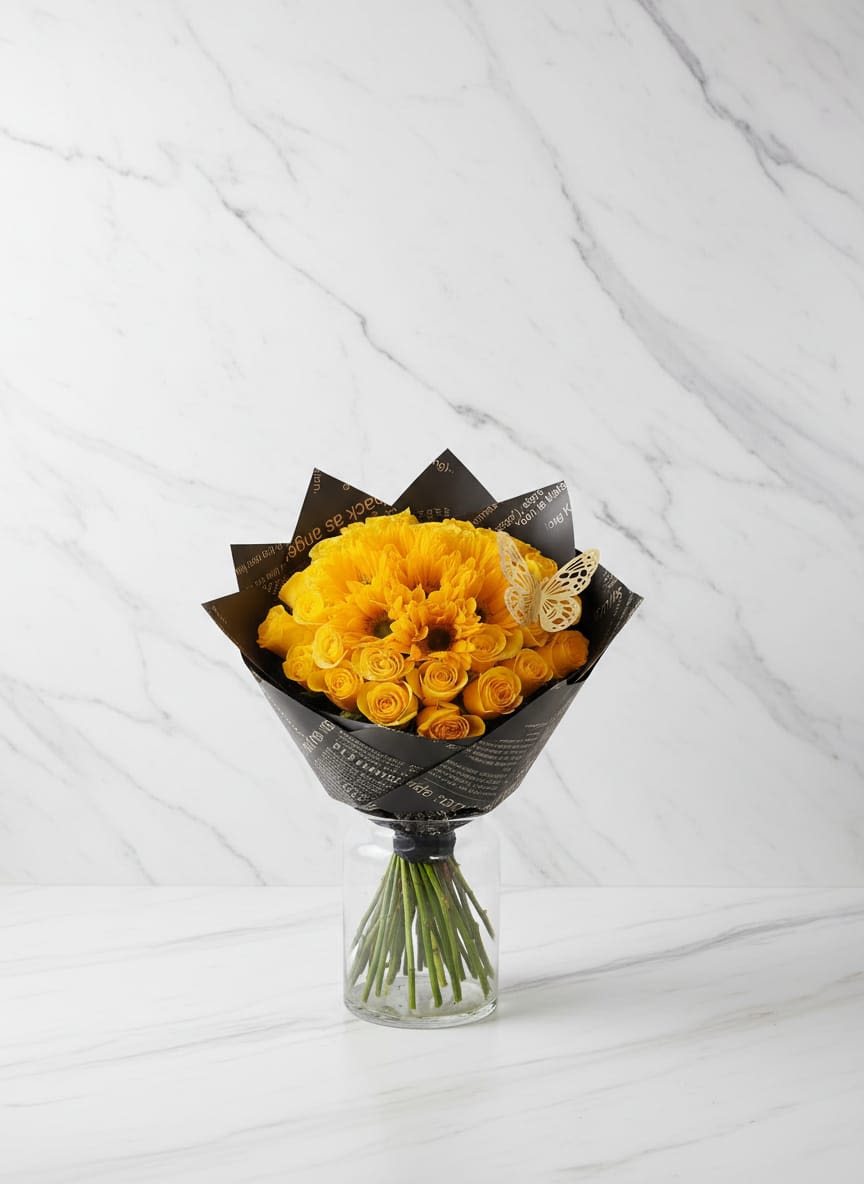 Sunny Hug Bouquet - Brighten someone's day with this cute Sunny Hug Bouquet, featuring vibrant yellow gerbera daisies surrounded by delicate yellow roses. Wrapped in stylish black floral paper with decorative lace details. The paper can change according to the client and the materials at hand. Ilumina el día de alguien con este lindo Ramo de Abrazo Soleado, que cuenta con vibrantes gerberas amarillas rodeadas por delicadas rosas amarillas. Envueltas con elegante papel floral negro con detalles de encaje decorativo. El papel puede cambiar según el cliente y los materiales disponibles.